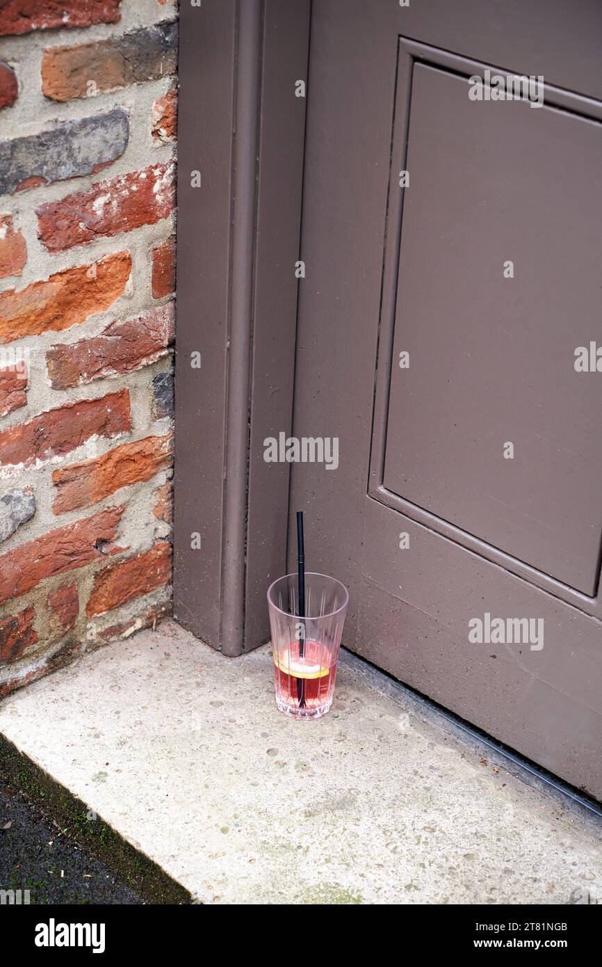 Bicchiere con cannuccia per bere lasciata sul gradino della porta Foto Stock