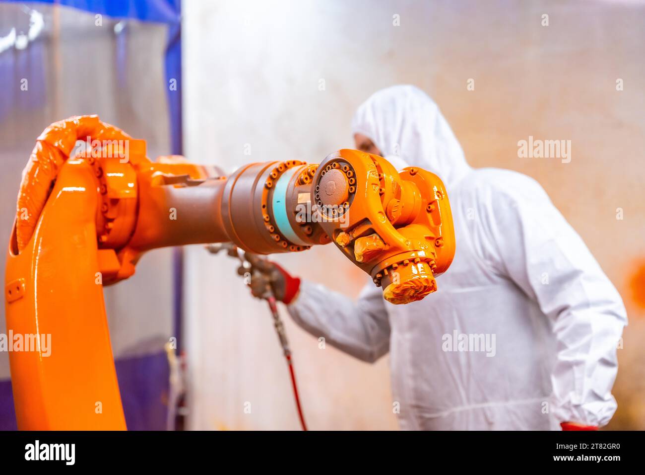 Pittore industriale con attrezzatura di protezione verniciatura di un braccio robotico con spray in un settore industriale di robot Foto Stock