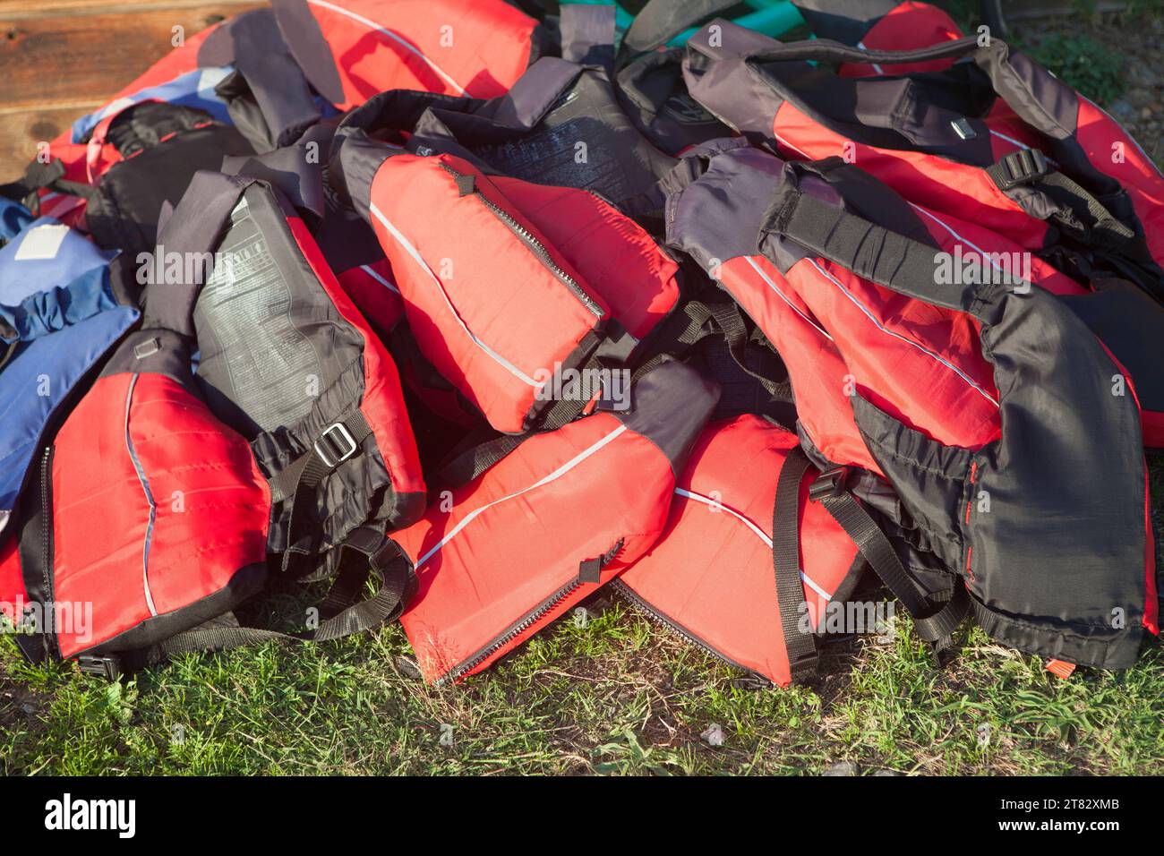 Giubbotti di salvataggio accumulati sull'erba. Concetto di turismo attivo sulle coste di acque dolci Foto Stock