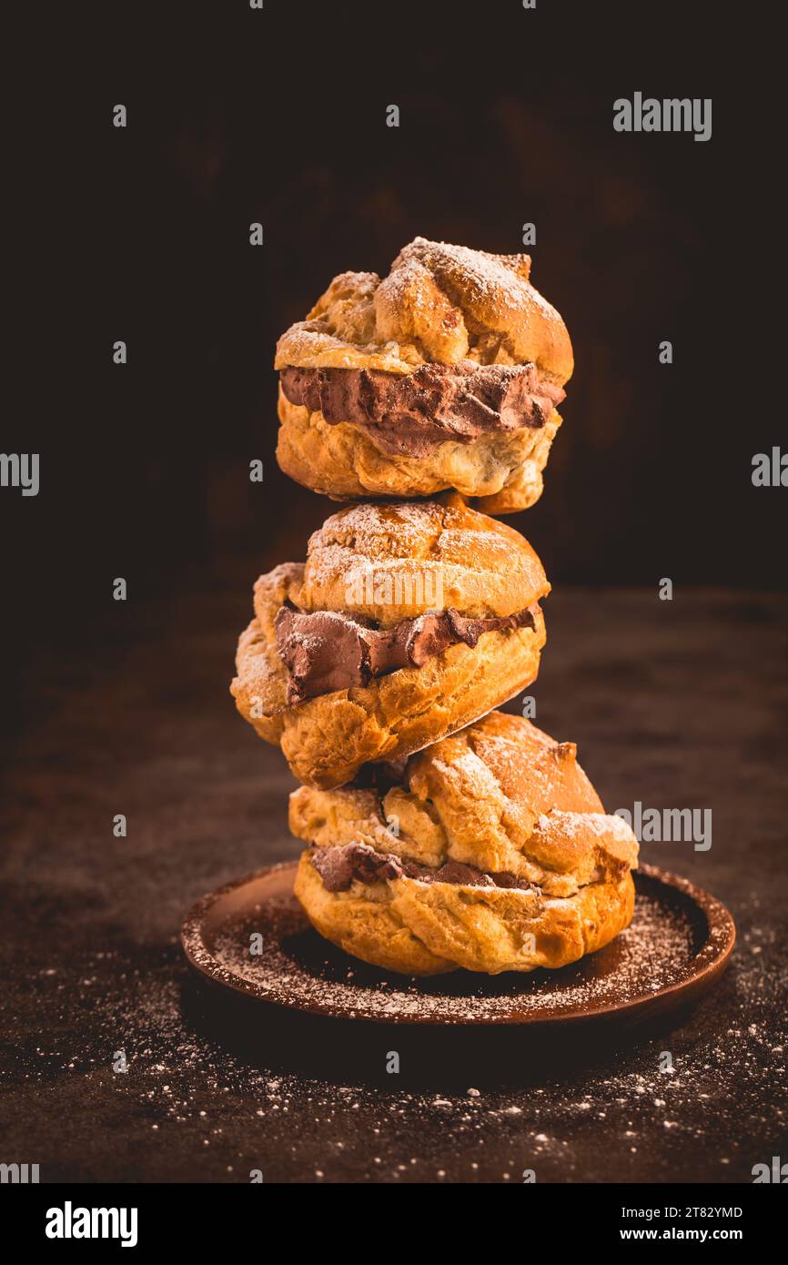 Profiteroles o crema ripiena con crema al cioccolato, palla di pasta sfoglia francese choux Foto Stock