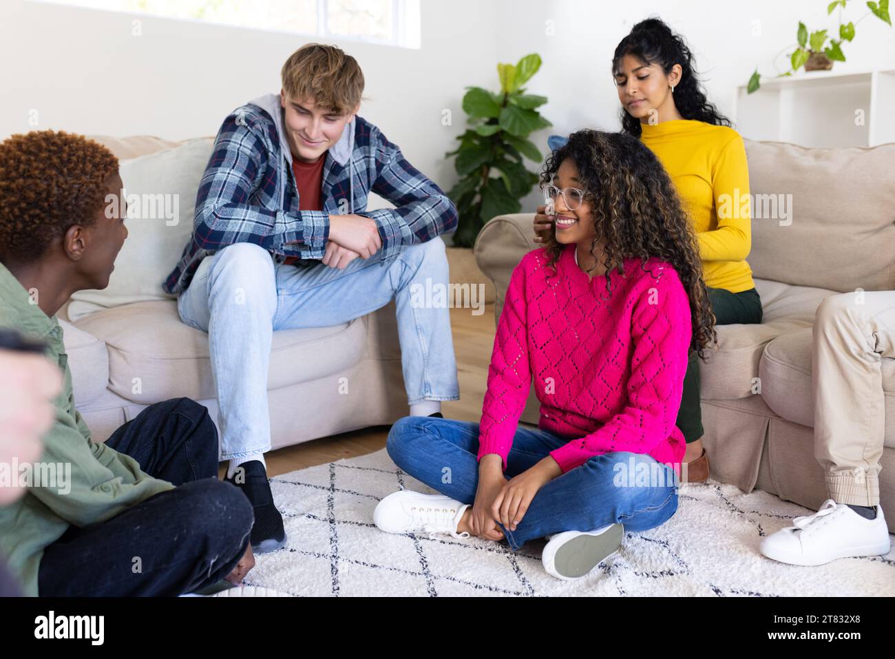 Allegri e diversificati amici adolescenti seduti sul divano e chiacchierando in cerchio a casa Foto Stock