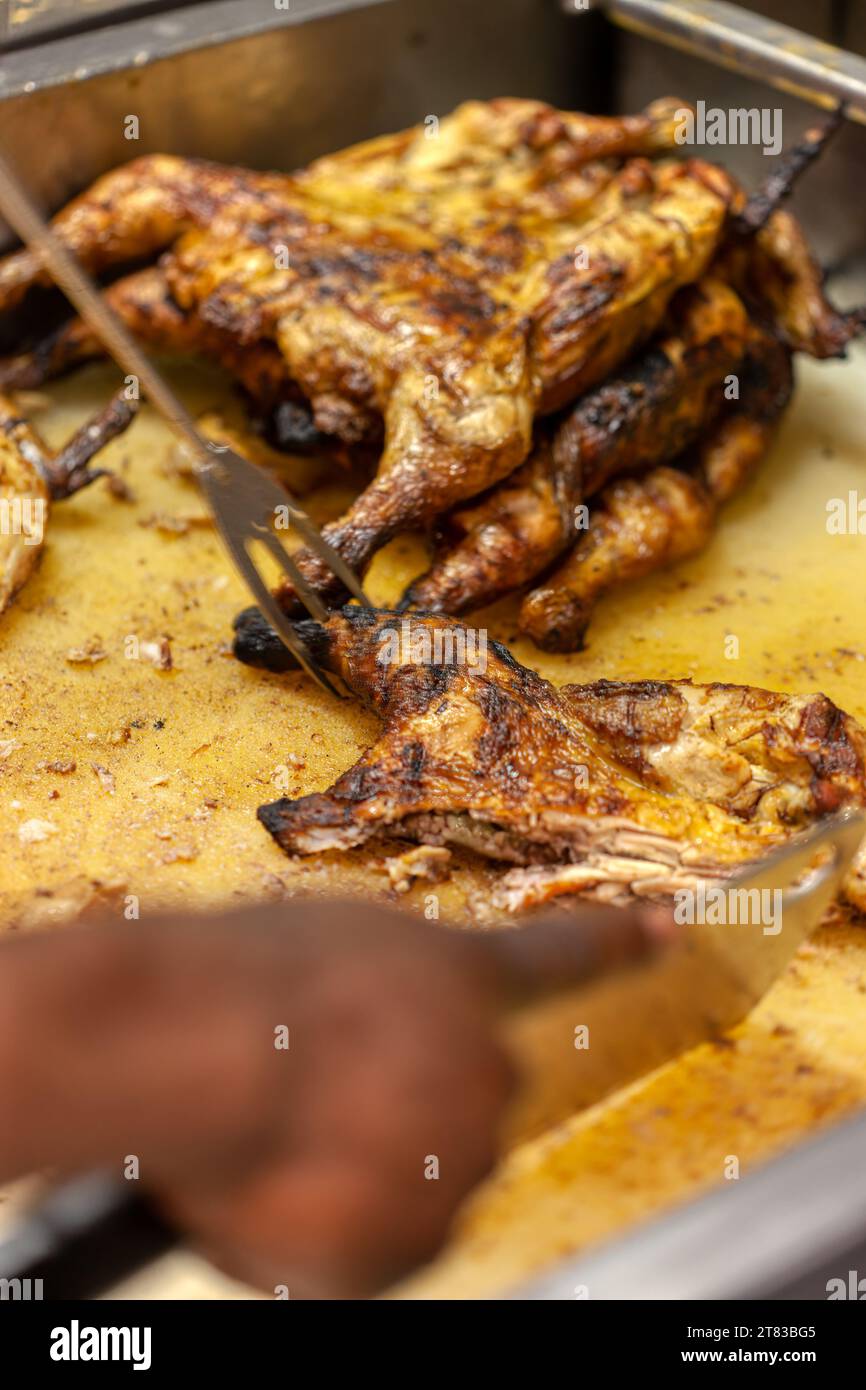 uomo afro-americano che taglia con un coltello pollo grigliato alla fiamma Foto Stock