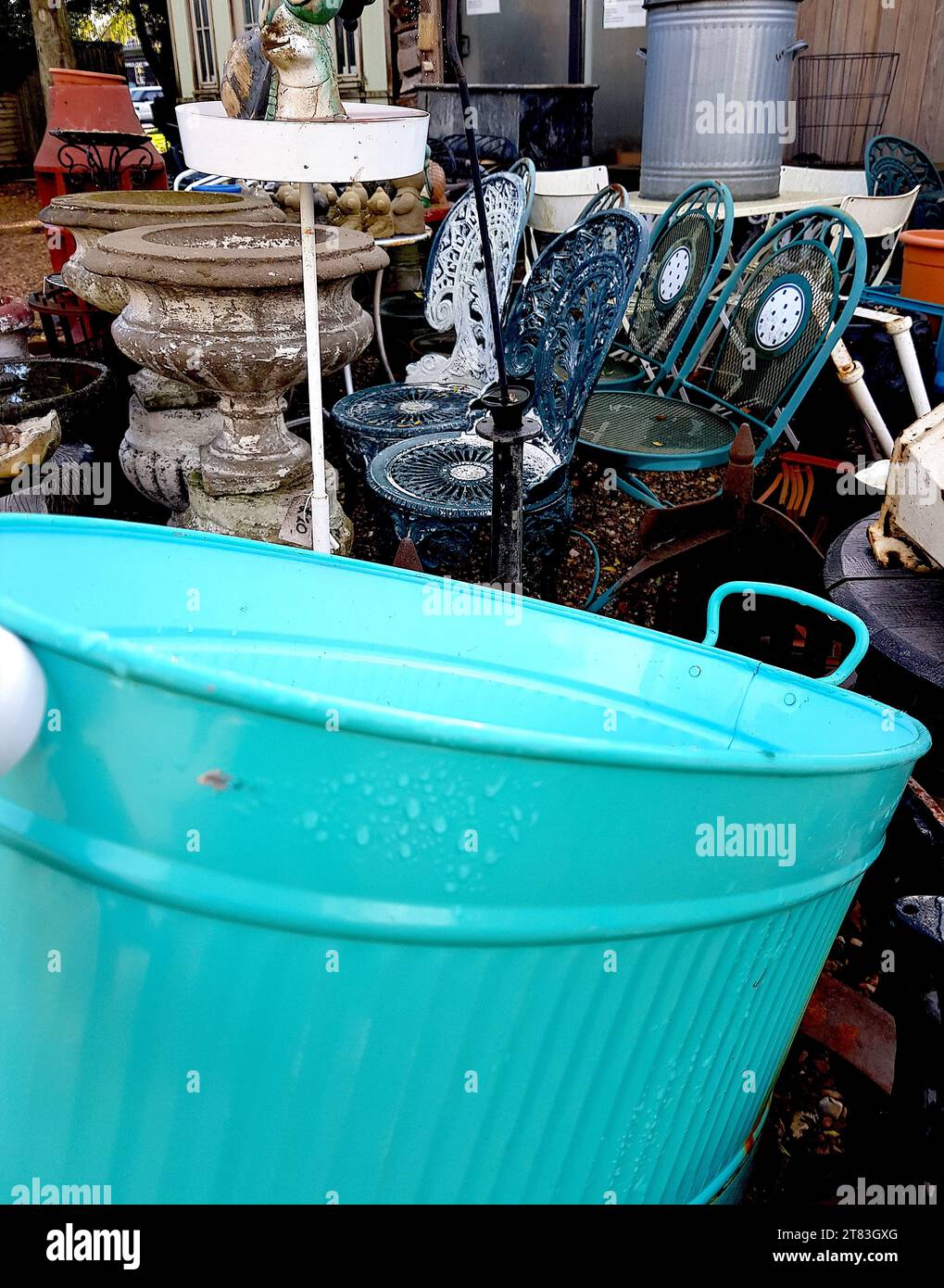 Primo piano di un giardino spazzatura con una vasca da bagno blu in primo piano. Foto Stock