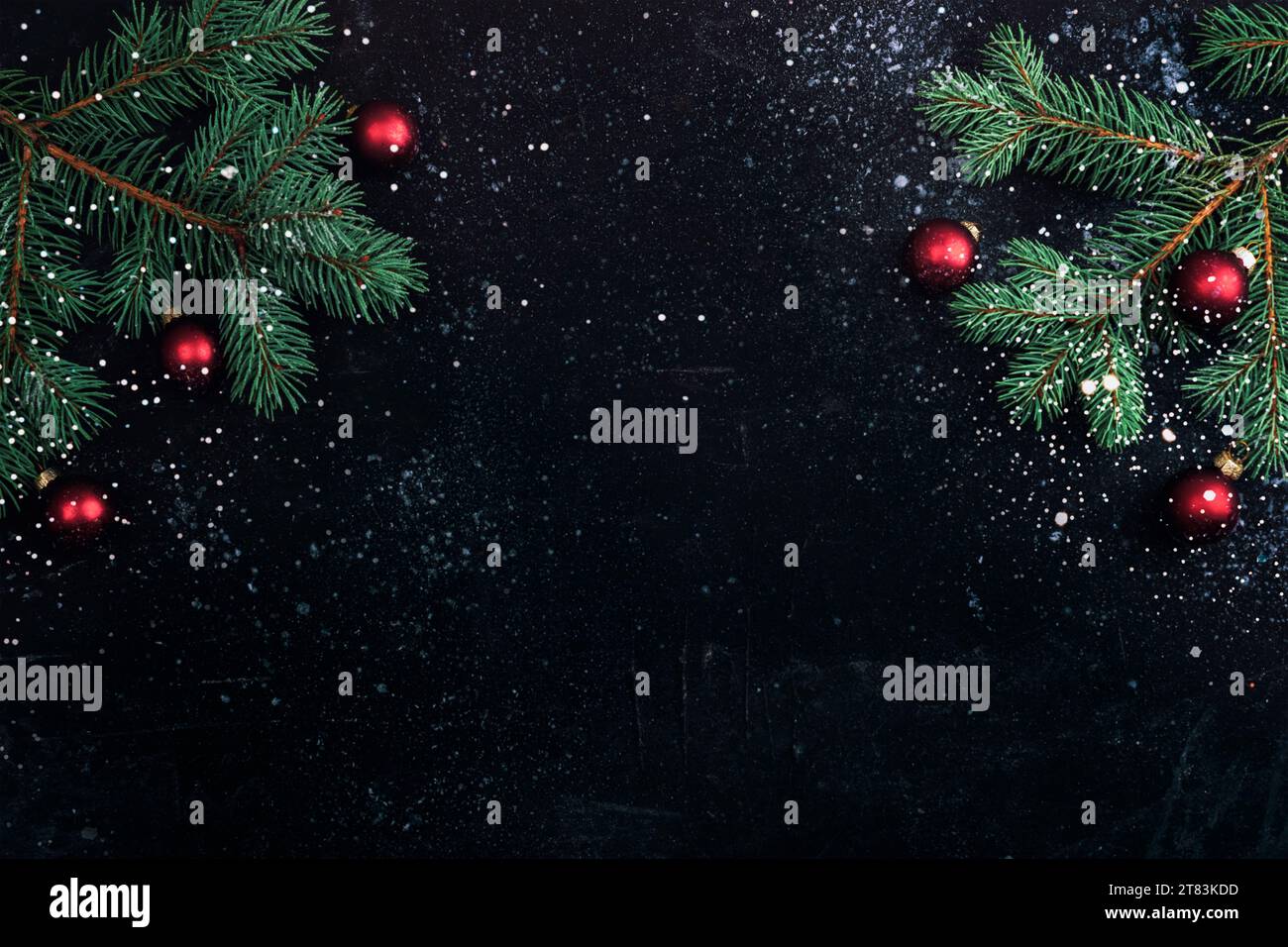 Rami dell'albero di Natale e palle rosse su sfondo nero con neve. Concetto di nuovo anno. Vista dall'alto, base piatta, spazio di copia. Foto Stock
