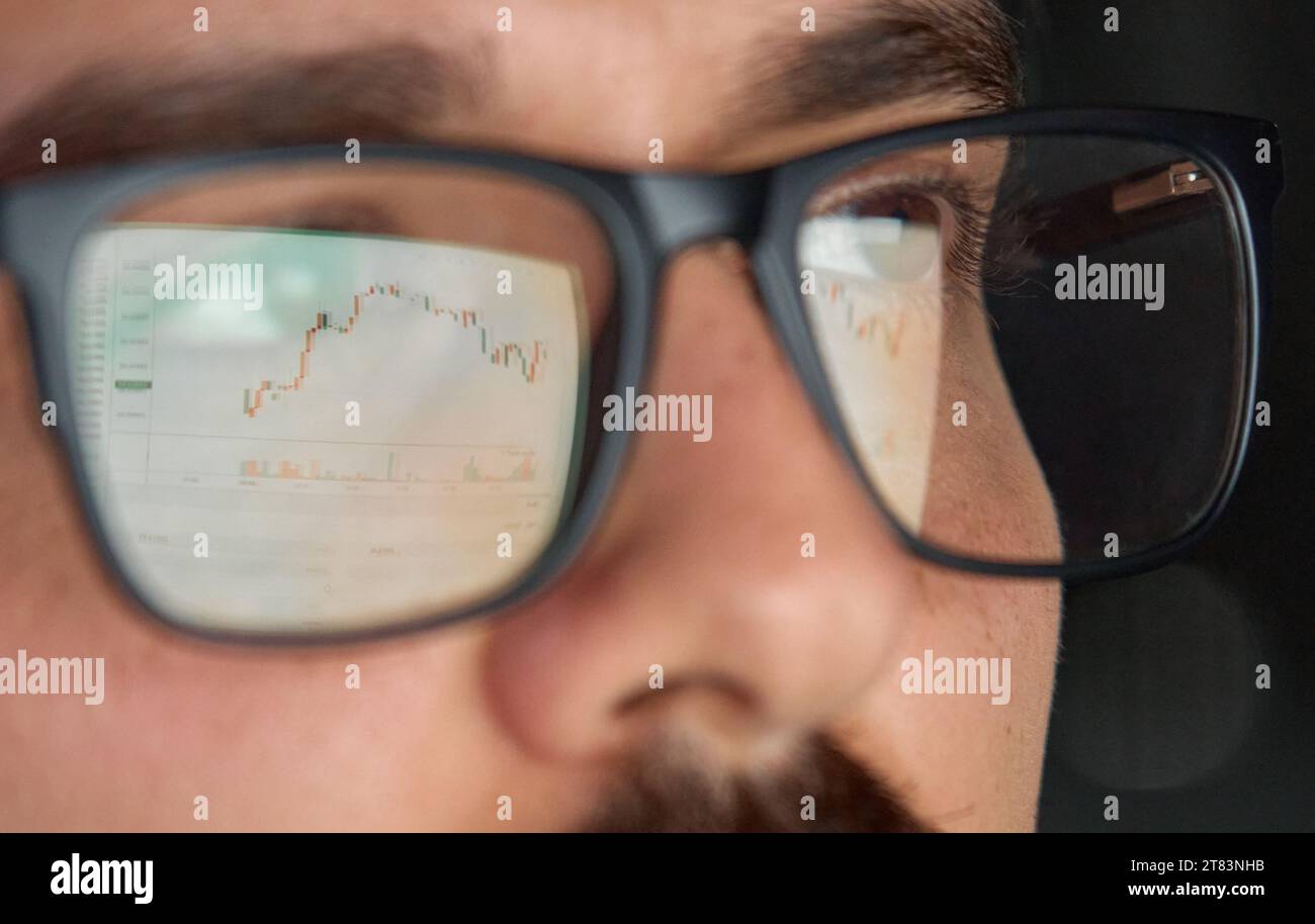Trader broker investitore che analizza il mercato azionario in occhiali con riflessione. Foto Stock