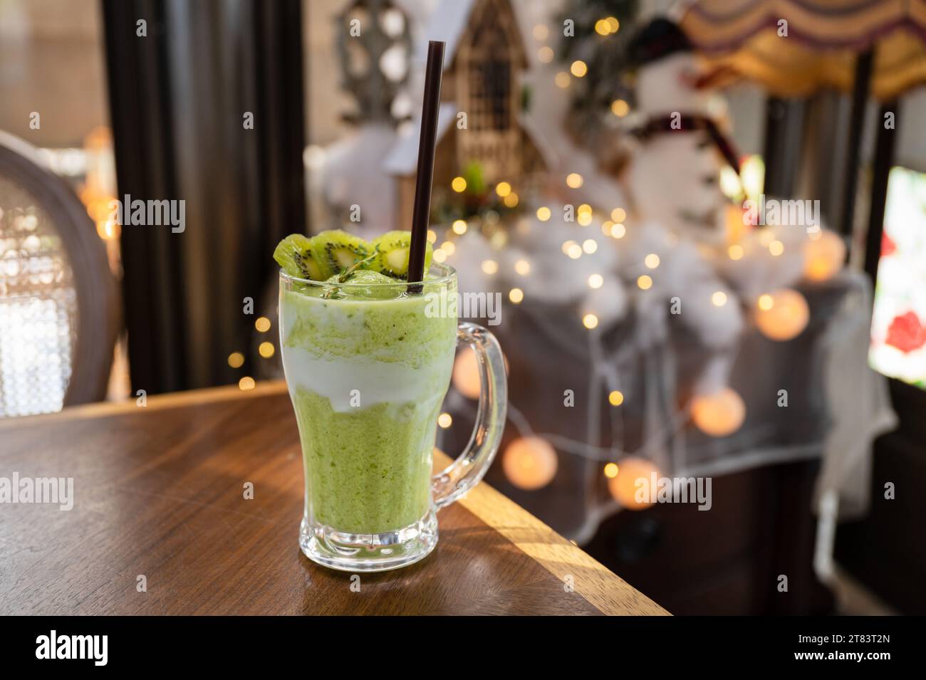 Frullato di frullato di succo di Kiwi in vetro su un tavolo di legno e su sfondo bokeh chiaro Foto Stock