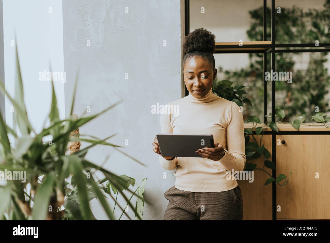Giovane donna afroamericana in piedi con un tablet digitale in ufficio Foto Stock