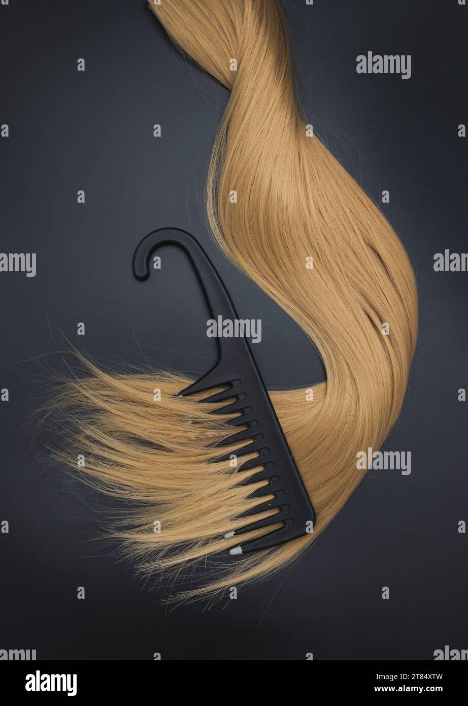 Composizione piatta con capelli chiari, pettine e spazio per il testo su sfondo nero. Servizio parrucchiere. Estensioni per capelli, materiali e cosmetici, capelli Foto Stock