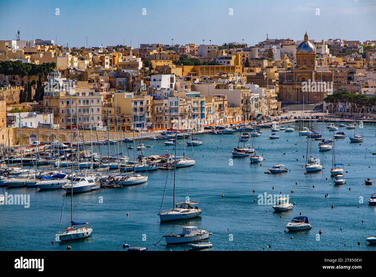 Le acque calme e le barche che circondano le tre città di fronte a la Valletta a Malta - Kalkara Village Parish Church Silver Dome Buildings Foto Stock