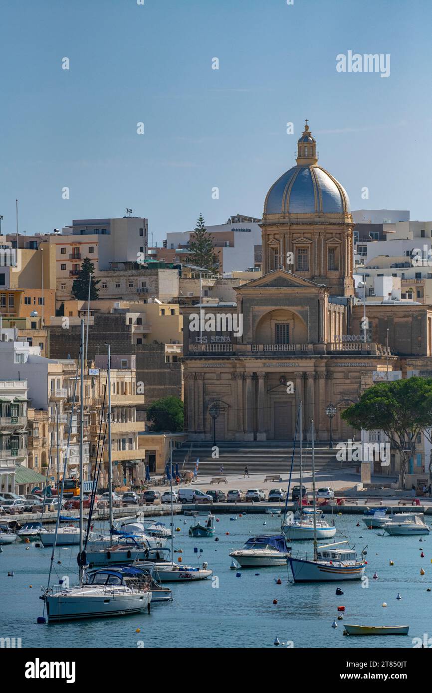 Le acque calme e le barche che circondano le tre città di fronte a la Valletta a Malta - Kalkara Village Parish Church Silver Dome Buildings Foto Stock