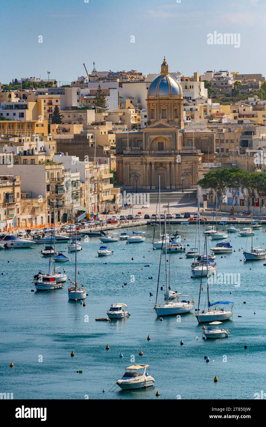 Le acque calme e le barche che circondano le tre città di fronte a la Valletta a Malta - Kalkara Village Parish Church Silver Dome Buildings Foto Stock