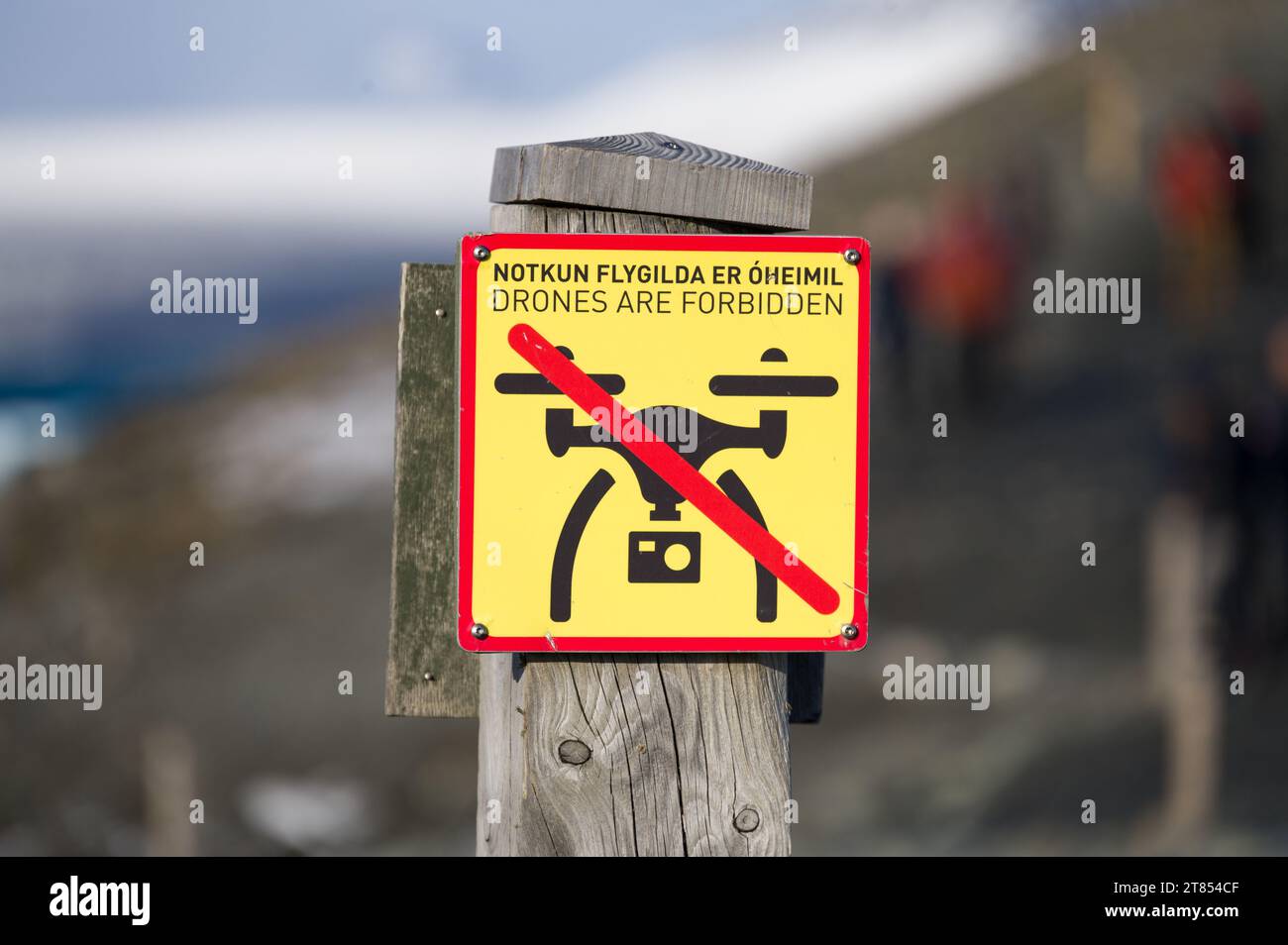 Un grande cartello su un palo di legno che indica i droni è proibito con la traduzione islandese, la laguna del ghiacciaio Jokulsarlon, l'Islanda Foto Stock