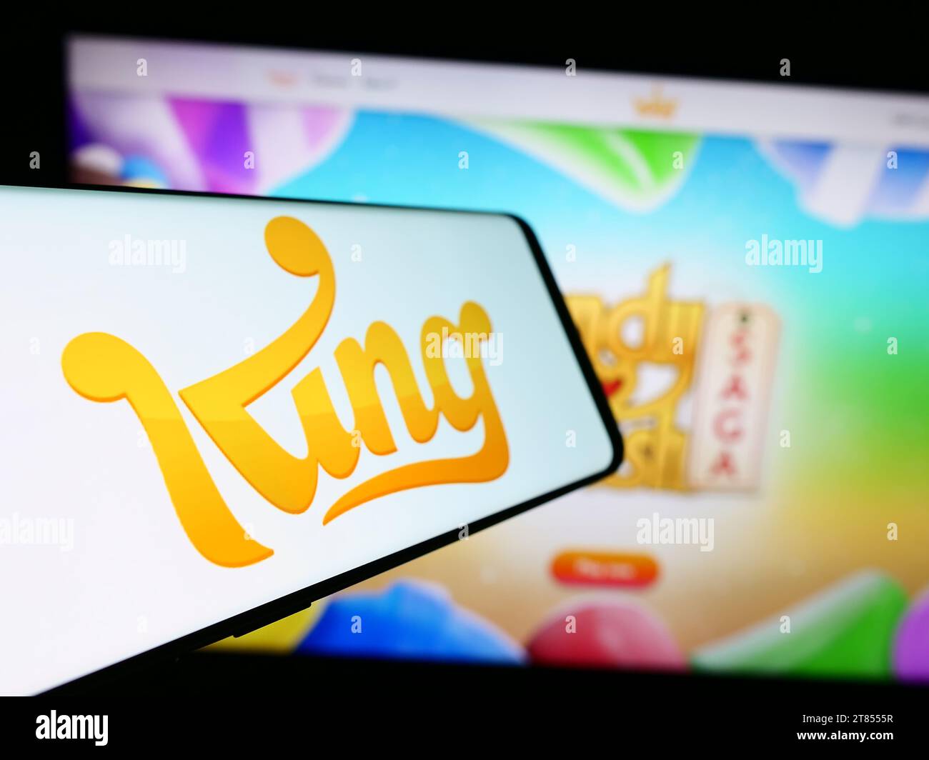 Smartphone con logo della società svedese di sviluppo di videogiochi King.com Limited davanti al sito Web. Mettere a fuoco il display centrale sinistro del telefono. Foto Stock