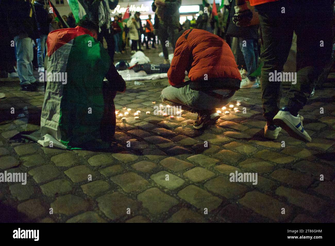 Flensburg, Schleswig-Holstein, Pro-Palästina-Demonstration a Flensburg. Personen zünden Kerzen an auf dem Boden des Südermarktes, im Hintergrund in weiße Laken gehüllte Puppen mit roten Flecken, Die Blut und getötete Personen symbolosieren sollen. Aufnahme vom 18.11.2023, Flensburg, Holm/Südermarkt *** Flensburg, Schleswig Holstein, manifestazione pro Palestina a Flensburg la gente accende candele sul pavimento del Südermarkt, sullo sfondo bambole avvolte in lenzuola bianche con macchie rosse che simboleggiano sangue e persone uccise foto scattata il 18 11 2023, Flensburg, Holm Südermarkt Foto Stock