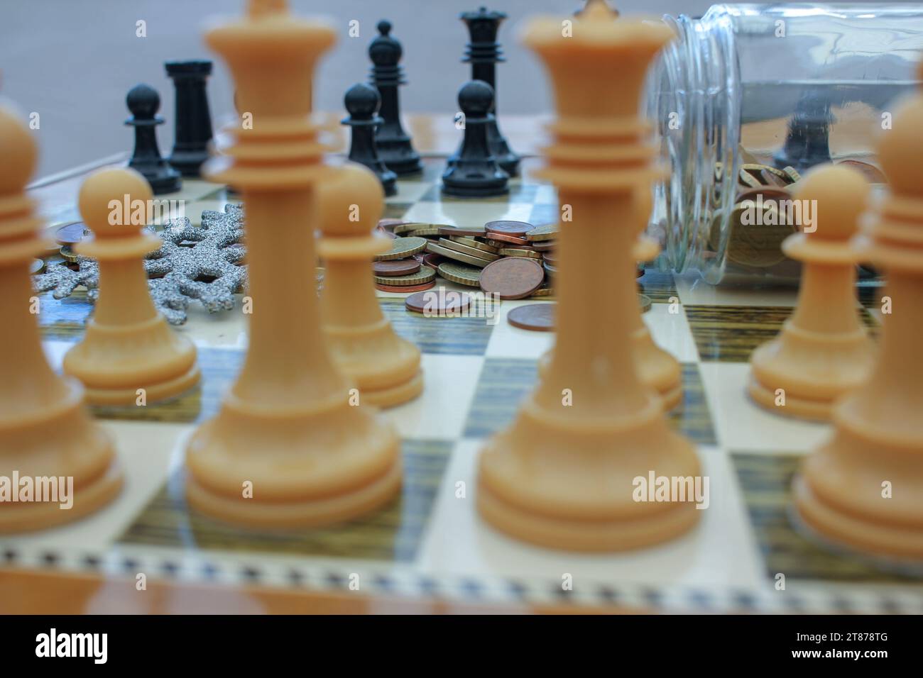 Ornamenti natalizi e monete su un tavolo da scacchi perché dovremo spendere un sacco di soldi nel periodo natalizio Foto Stock