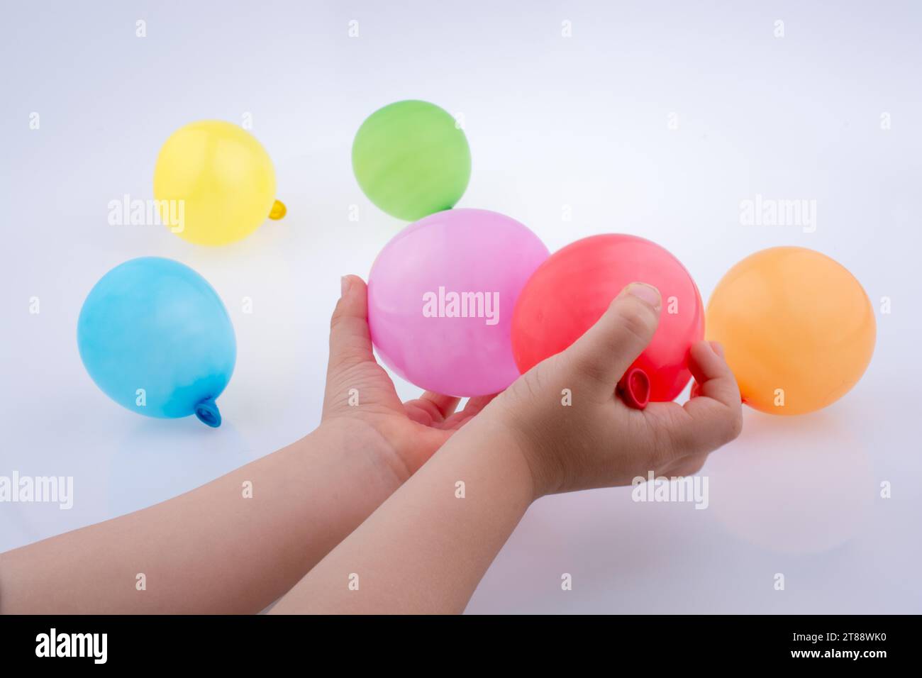 Mano che tiene un palloncino colorato con palloncini colorati sullo sfondo bianco Foto Stock
