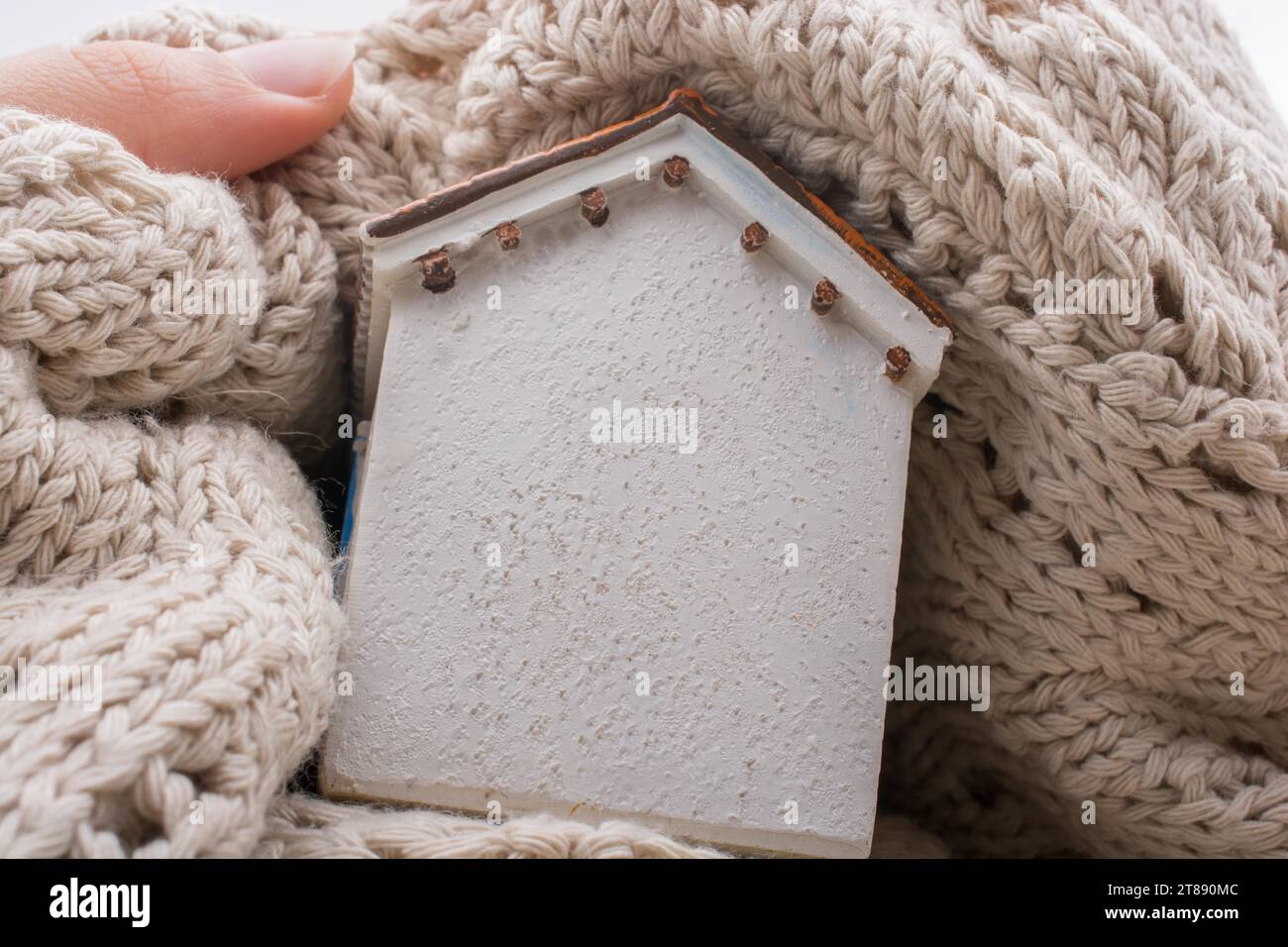 Piccola casa modello avvolto in stoffa su un sfondo marrone Foto Stock