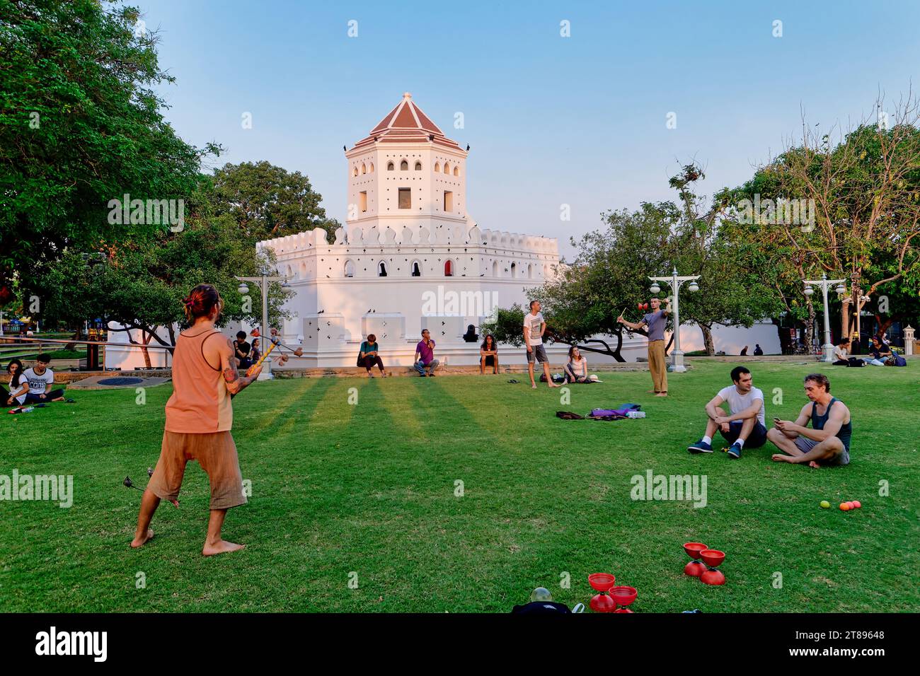 Turisti stranieri che si rilassano nel Parco Santichaiprakarn a Banglamphu, (Banglamphoo), Bangkok, Thailandia, il vecchio forte di Phra Sumen sullo sfondo Foto Stock