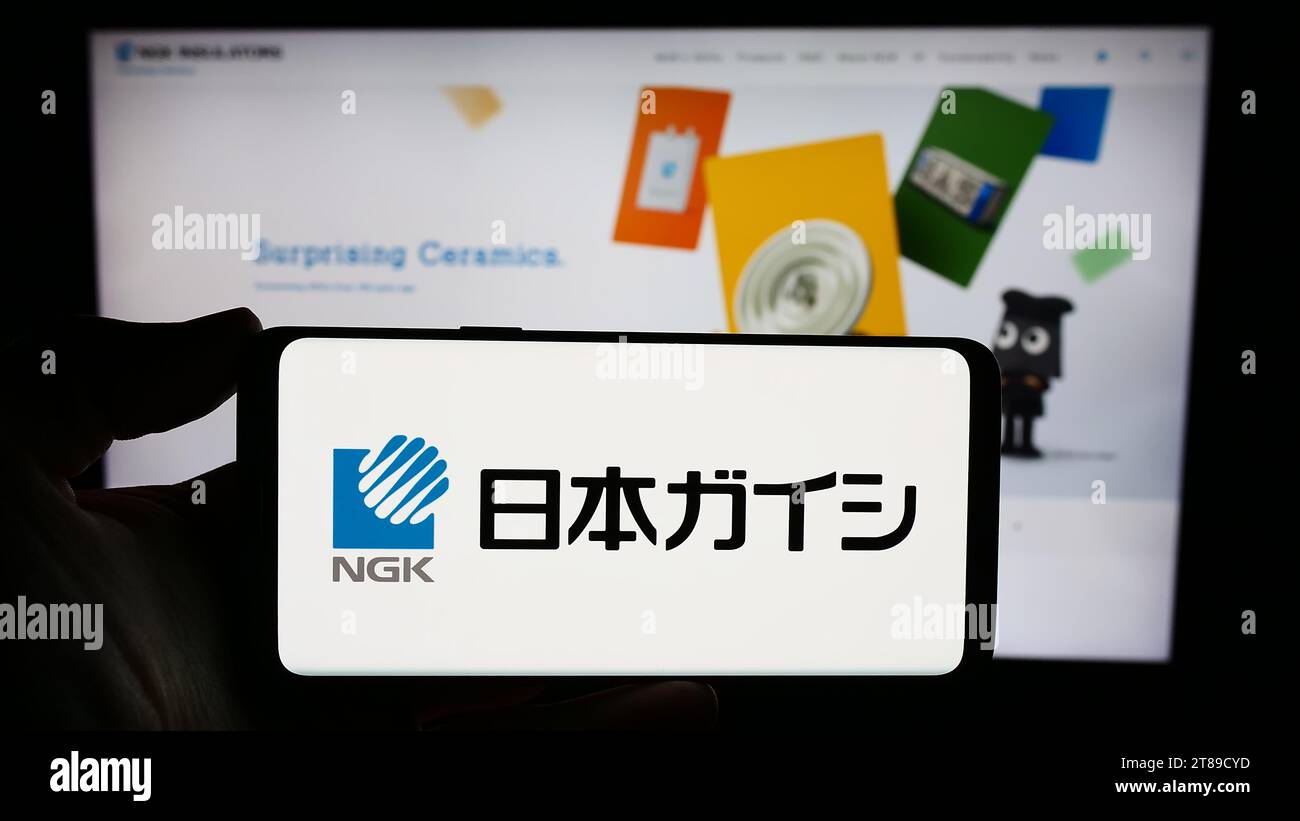 Persona che possiede uno smartphone con il logo della società giapponese di ceramica NGK Insulators Ltd. Davanti al sito Web. Concentrarsi sul display del telefono. Foto Stock