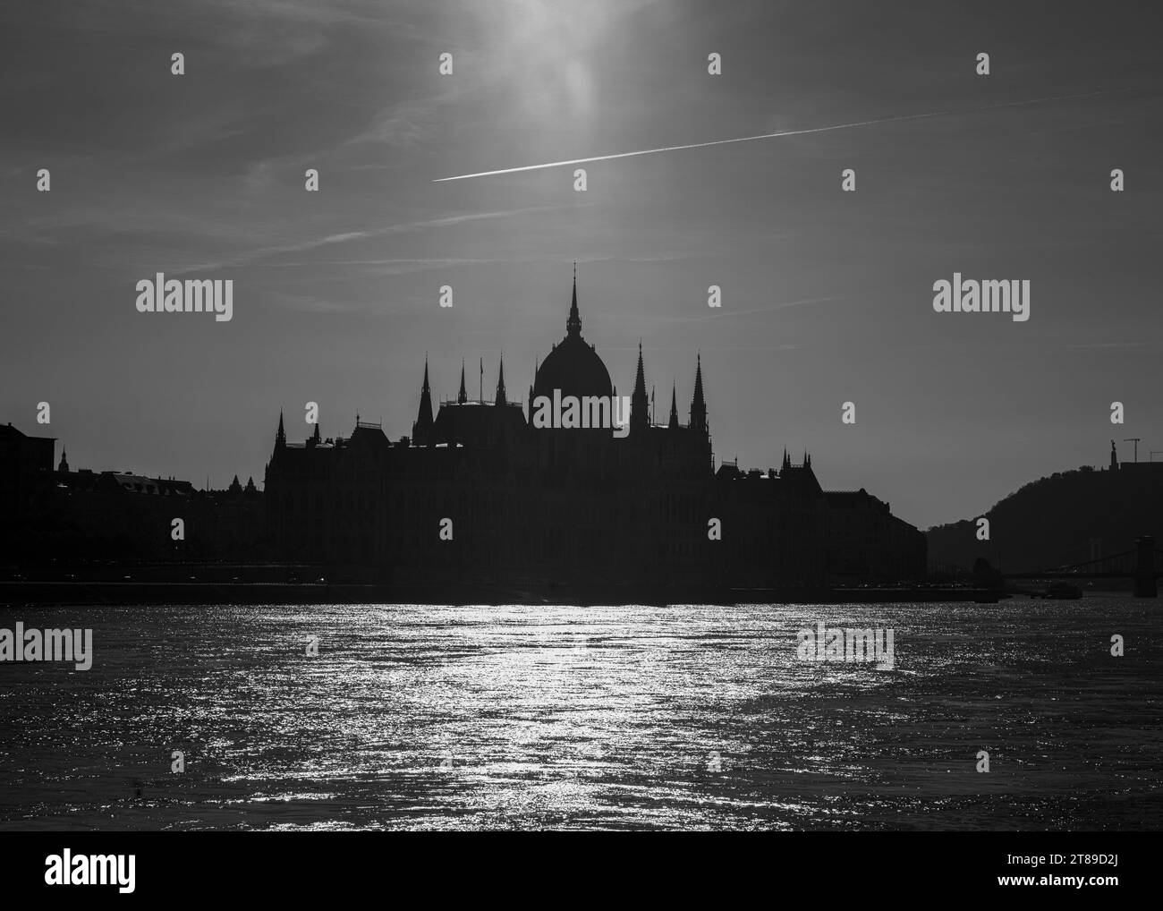 L'iconico ma grande Parlamento ungherese visto dal fiume Danubio e retroilluminato Foto Stock