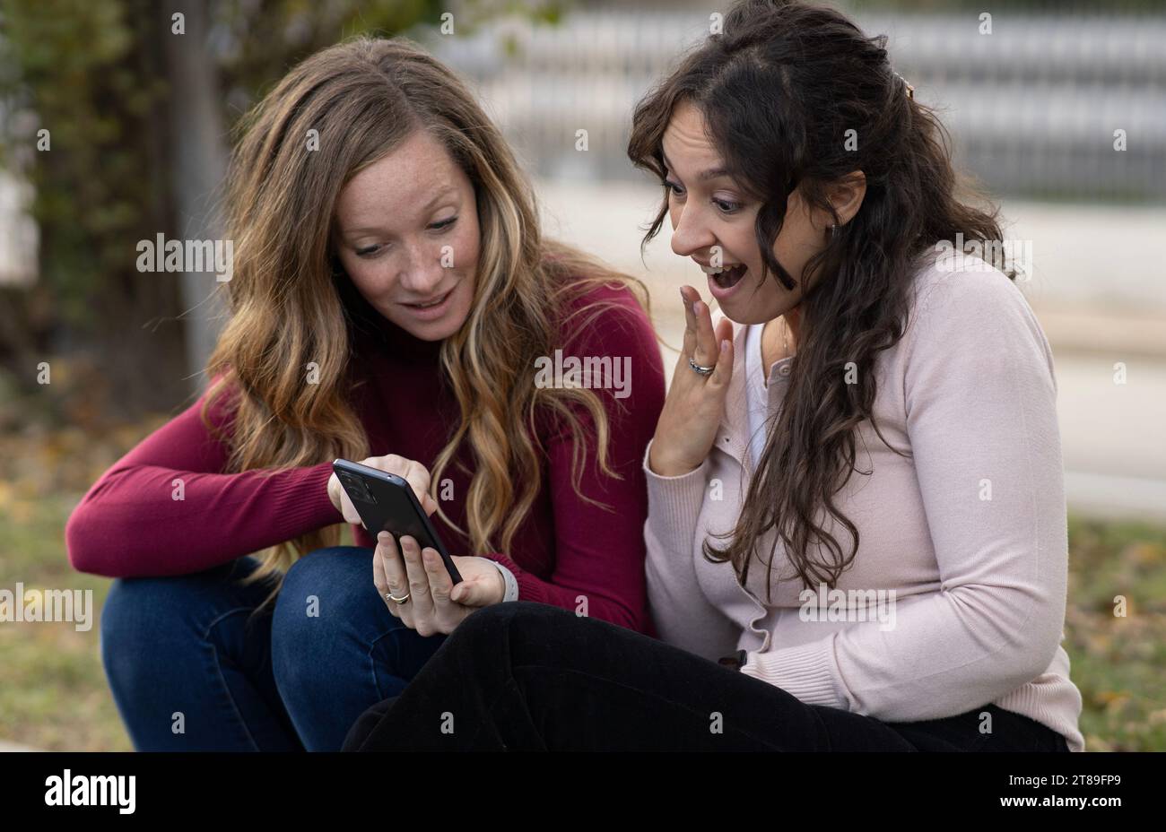 Un paio di ragazze scioccate da ciò che vedono sullo smartphone.pettegolezzi online. Foto Stock
