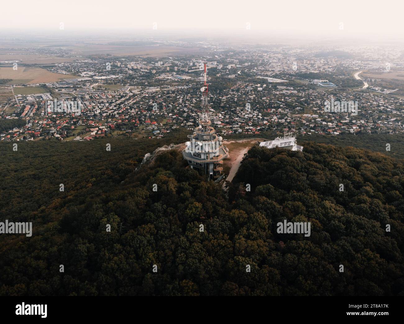 Foto aerea della torre del trasmettitore sulla collina di Zobor a Nitra - Slovacchia. Volo con drone sopra la collina e la grande città vicino alla foresta. Foto Stock