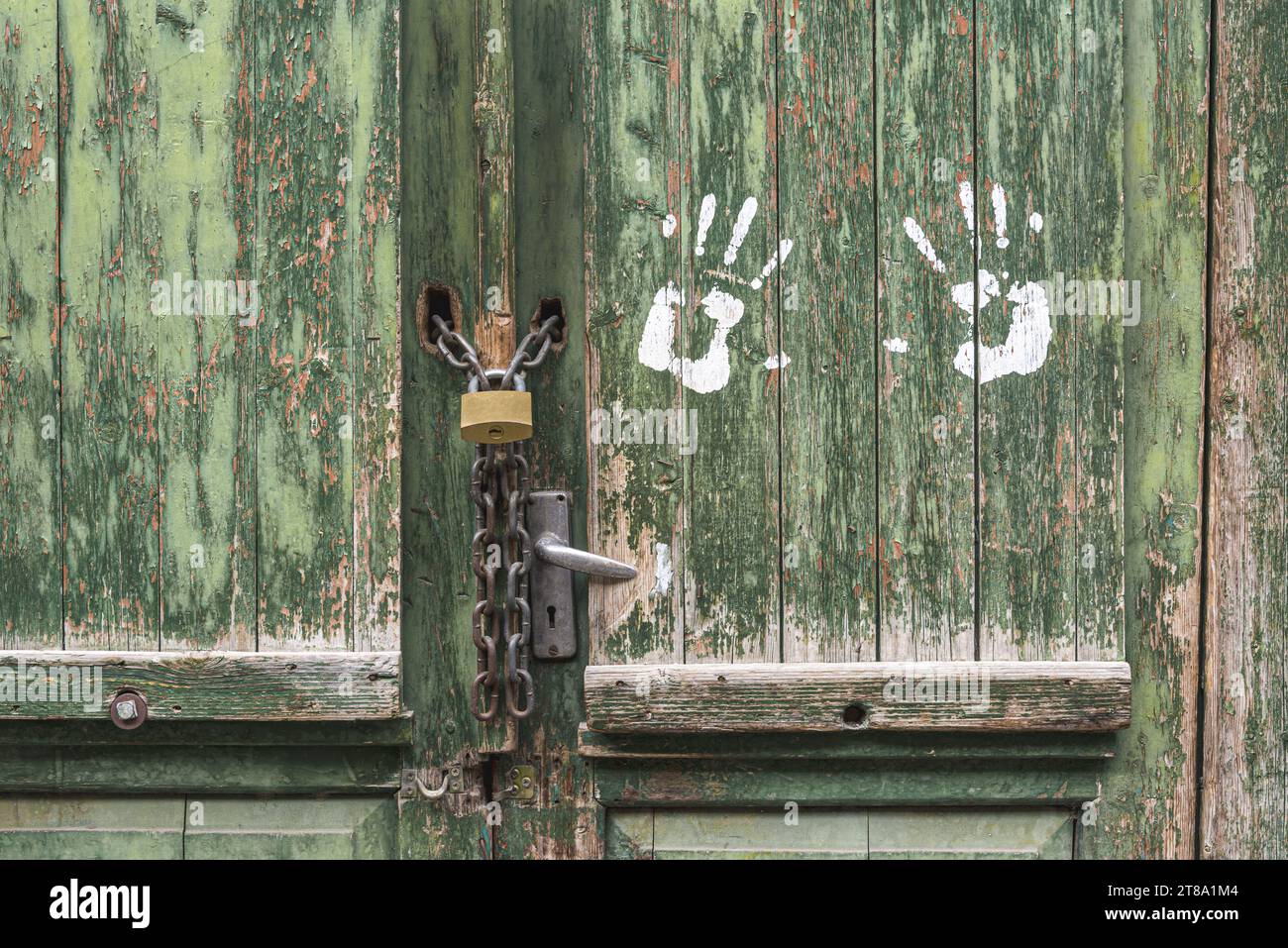 Una vecchia porta di legno verde, chiusa su un lucchetto. Foto Stock