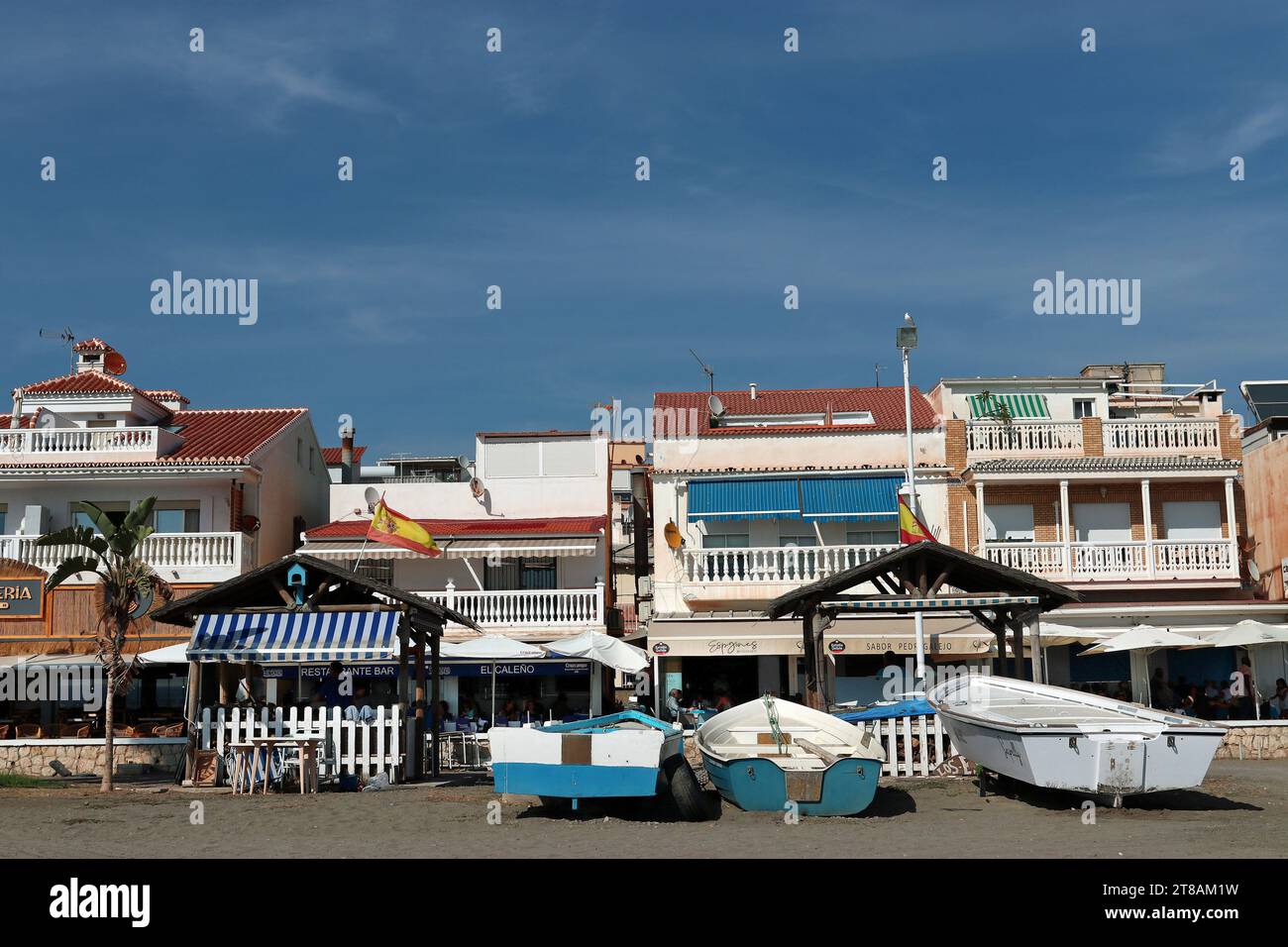 Villaggio di pescatori di Pedregalejo, Malaga: Le barche da pesca si trovano sulla sabbia di fronte al lungomare con i suoi chiringuitos e bancarelle di barbecue a base di pesce Foto Stock
