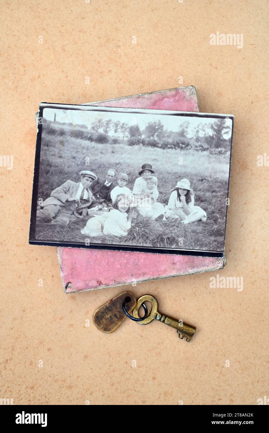 Stampa monocromatica della famiglia operaia inglese degli anni '1920 con un'antica chiave in ottone e una vecchia scatola rosa Foto Stock