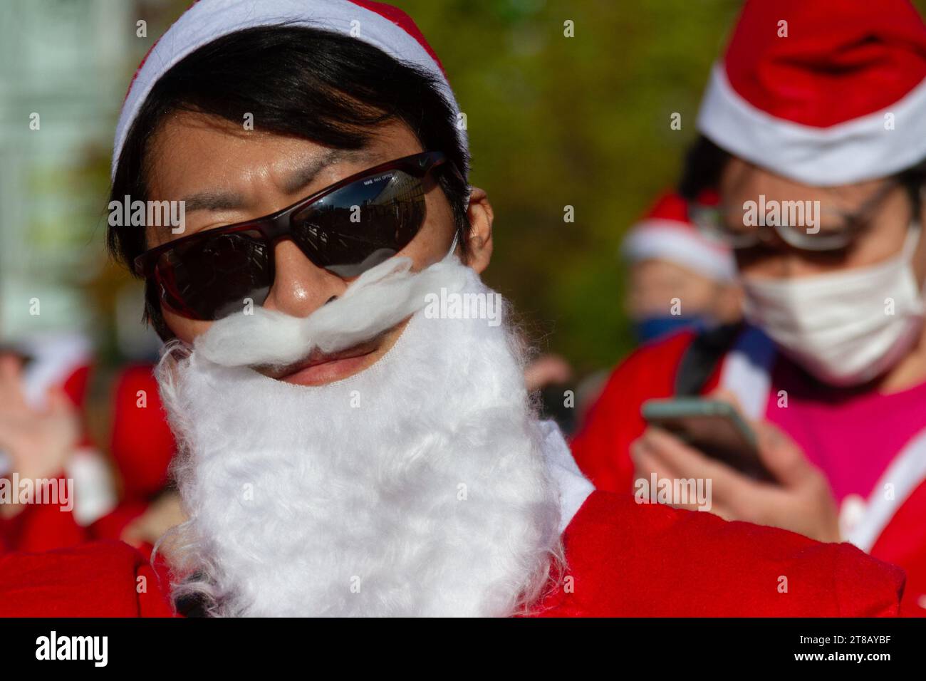 Tokyo, Giappone. 19 novembre 2023. Un uomo giapponese che indossa occhiali da sole e una barba di Babbo Natale si unisce a centinaia di persone che indossano costumi di Babbo Natale che partecipano alla sesta edizione annuale della Tokyo Great Santa Run. La corsa è iniziata nel parco Yoyogi prima di sfilare attraverso Shibuya e Harajuku ed è stata un evento di beneficenza per raccogliere fondi per i bambini malati in Giappone e all'estero. Credito: SOPA Images Limited/Alamy Live News Foto Stock