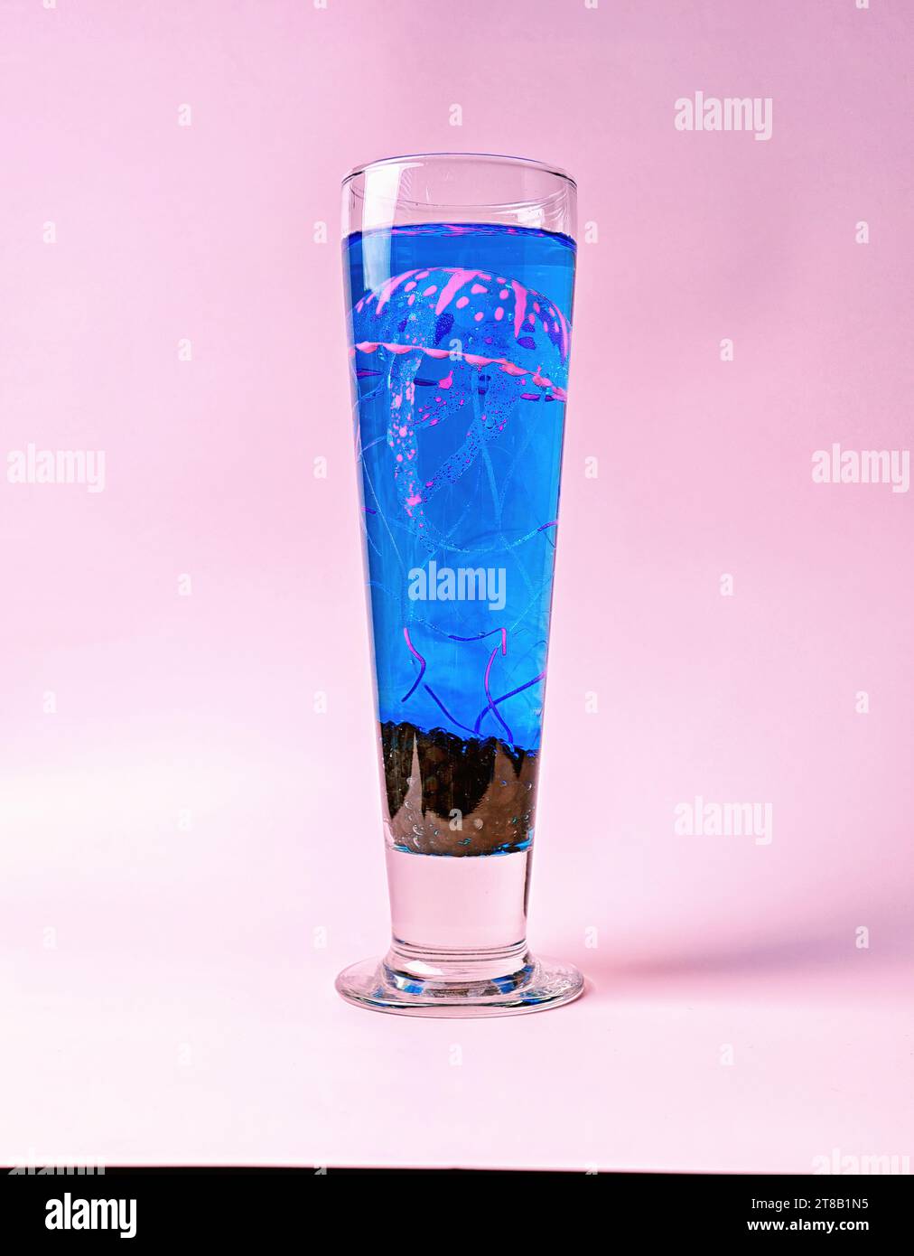 Jellyfish elettrica: Una medusa rosa e blu al neon in un bicchiere di birra su sfondo rosa - concetto di evento Marine Life and Aquarium Foto Stock