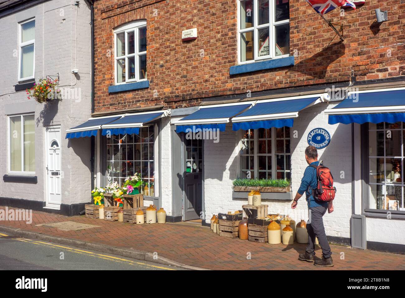 Uomo che cammina accanto al piccolo negozio indipendente Temptations, lungo Wheelock Street, nella città del Cheshire, Middlewich, Inghilterra Foto Stock