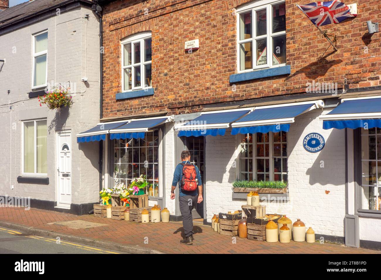 Uomo che cammina accanto al piccolo negozio indipendente Temptations, lungo Wheelock Street, nella città del Cheshire, Middlewich, Inghilterra Foto Stock