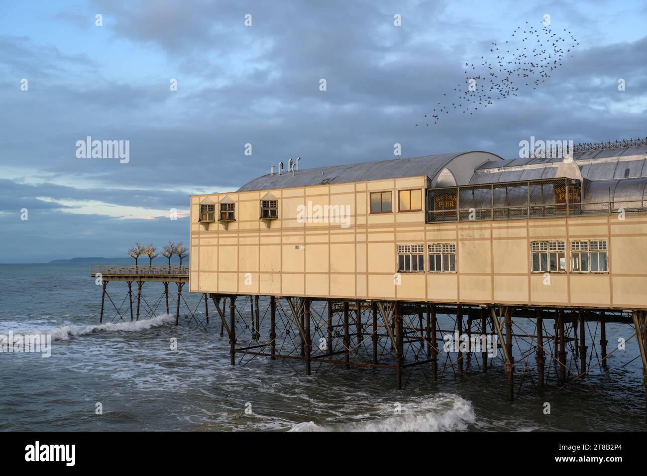 Stelle che volano sopra il Royal Pier Arcade al crepuscolo, Aberystwyth Pier, Galles del Nord Foto Stock