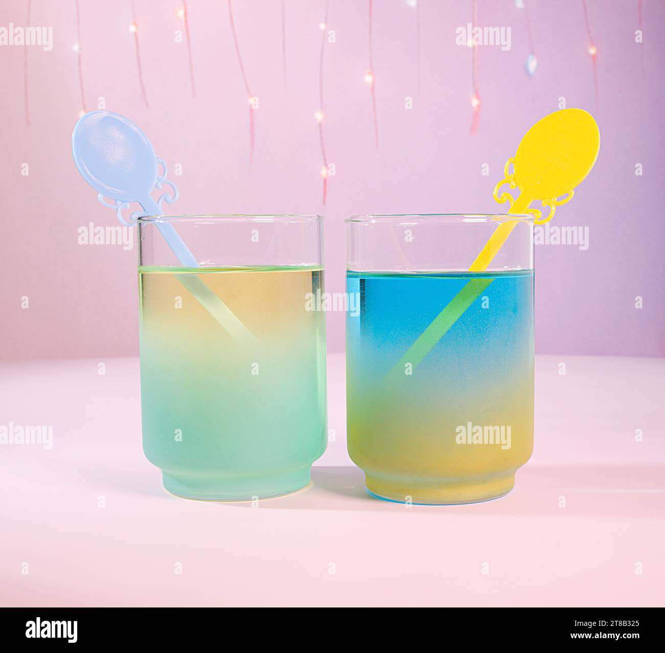 Un Duo di cocktail primaverile pastello: Due colorate bevande blu e verdi pastello con un bastoncino Swizzle decorato in stile vittoriano con luci Fairy e schienale rosa Foto Stock