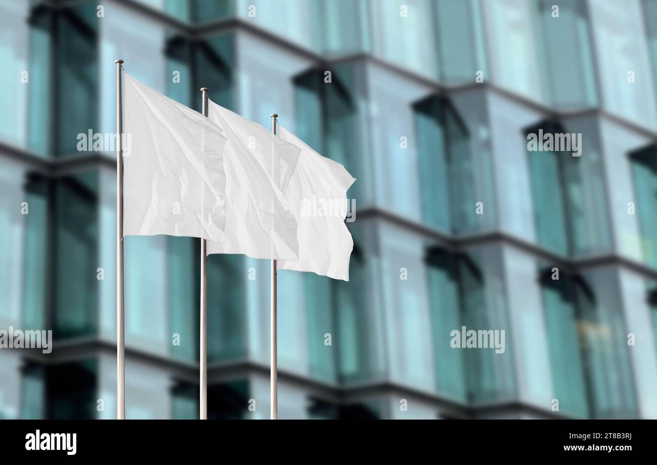Un gruppo di bandiere aziendali bianche contro un edificio di uffici sfocato. Modello di flag vuoto per aggiungere qualsiasi logo, simbolo o segno Foto Stock