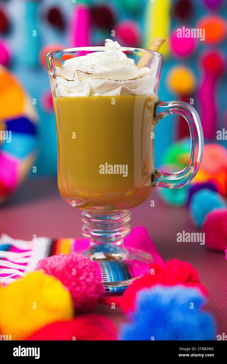 caffè messicano in una tazza di vetro ricoperta di panna montata e stecca di cannella Foto Stock