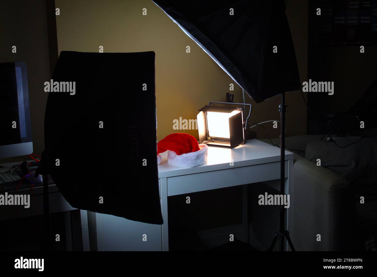 Una foto di uno studio fotografico a casa con luci da studio e un cappello di natale come soggetto su una scrivania bianca. Foto Stock