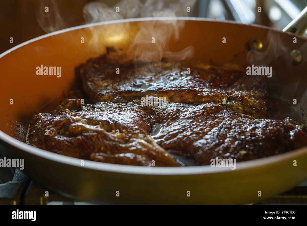 Bistecca di manzo che stuzzica su una padella calda, momento da vicino di perfezione culinaria sulla stufa. Foto Stock