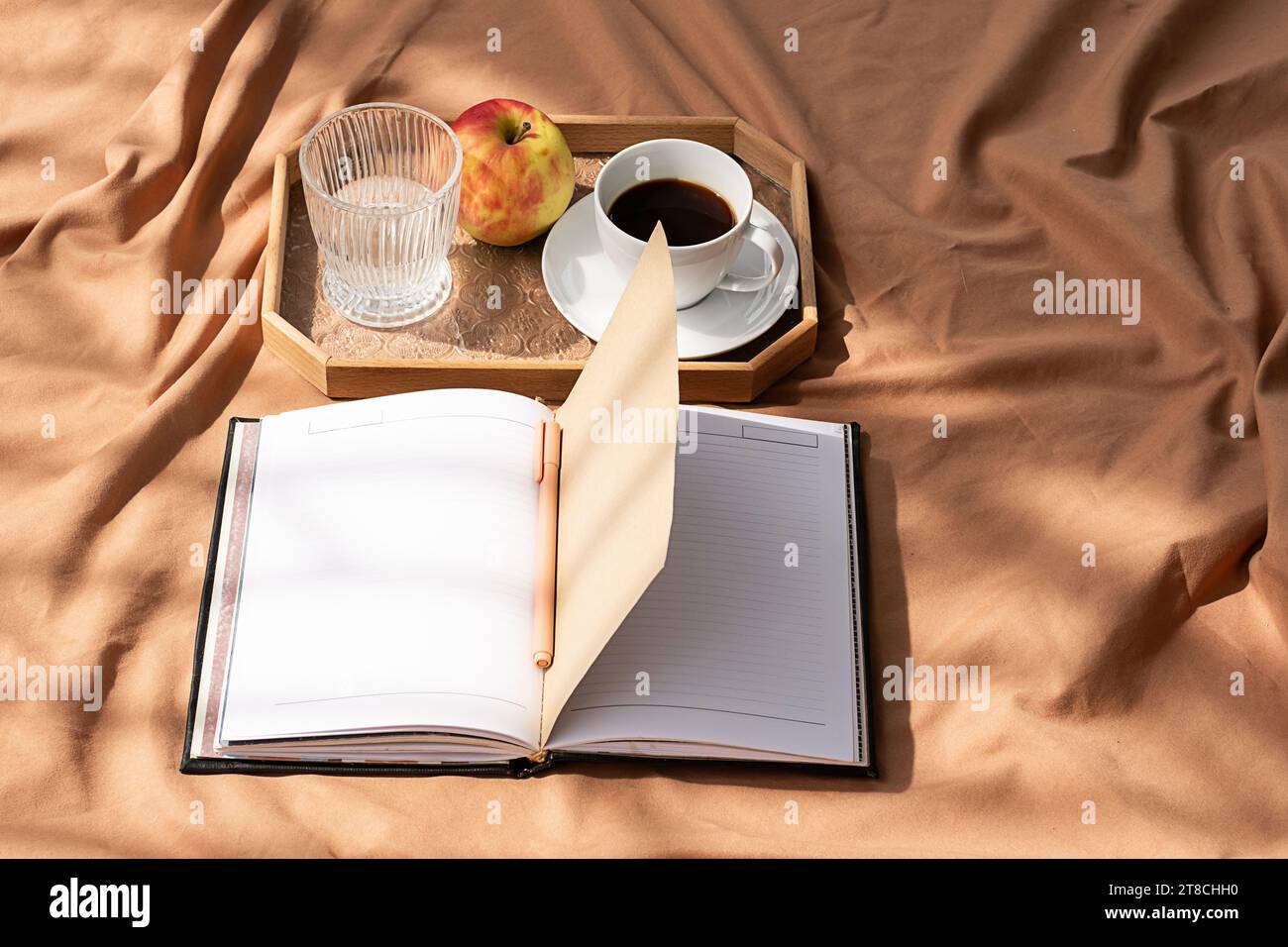 Aprire il notebook e la tazza di caffè sul vassoio Una mattinata intima a letto. Foto Stock