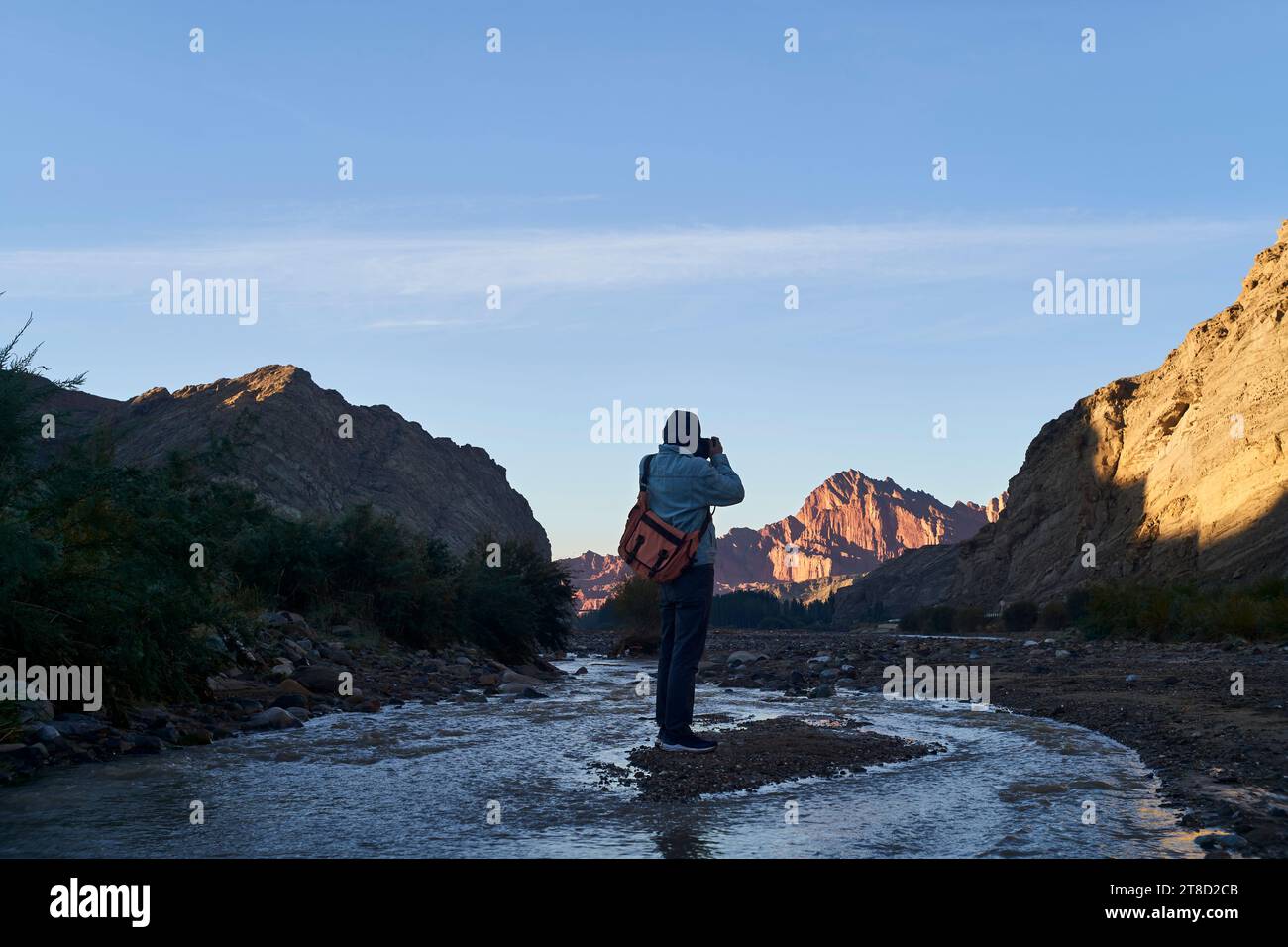 Vista posteriore del fotografo asiatico che scatta foto dell'alba al misterioso Grand Canyon di Tianshan, nello Xinjiang, in Cina Foto Stock