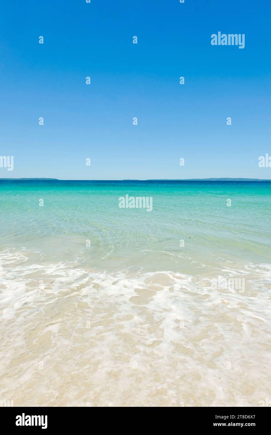 Acque cristalline turchesi, cieli blu senza nuvole, schiuma marina e sabbia bianca in una giornata di sole a Callala Beach a Shoalhaven, parco nazionale di Jervis Bay, New South Wales Foto Stock
