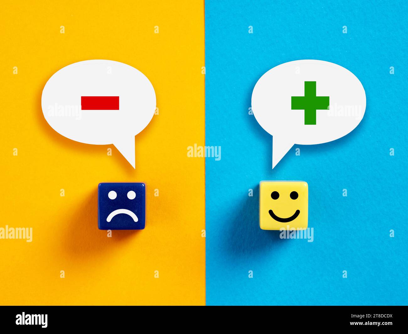 Pensiero o mentalità positiva o negativa. Cubi con volti felici e infelici con simboli più e meno nelle bolle vocali. Foto Stock