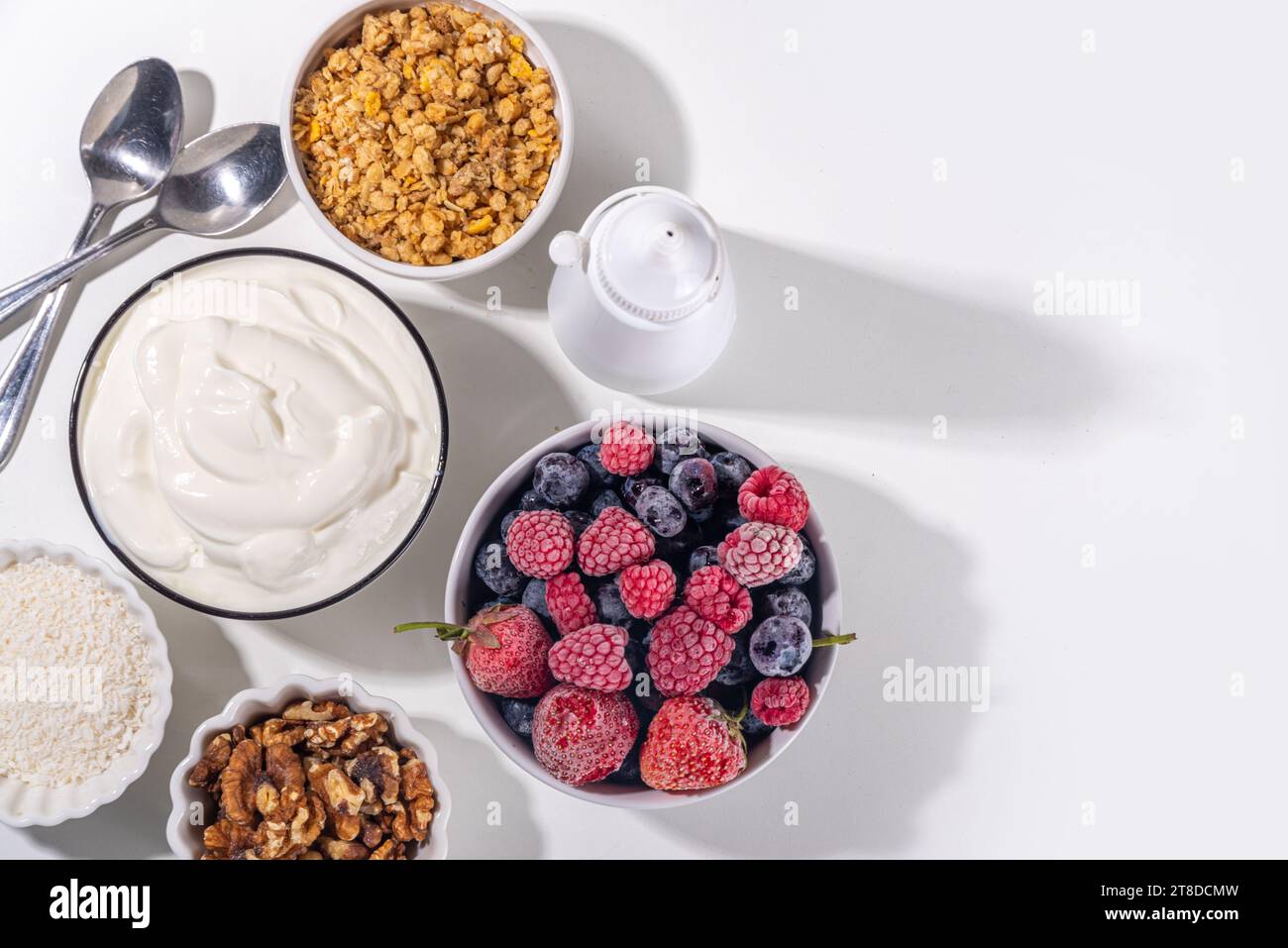 Preparazione della cottura con sfondo di corteccia di yogurt congelato con yogurt greco, bacche fresche, muesli, miele, salsa al cioccolato, con vassoio da forno deco. Vista dall'alto della donna Foto Stock