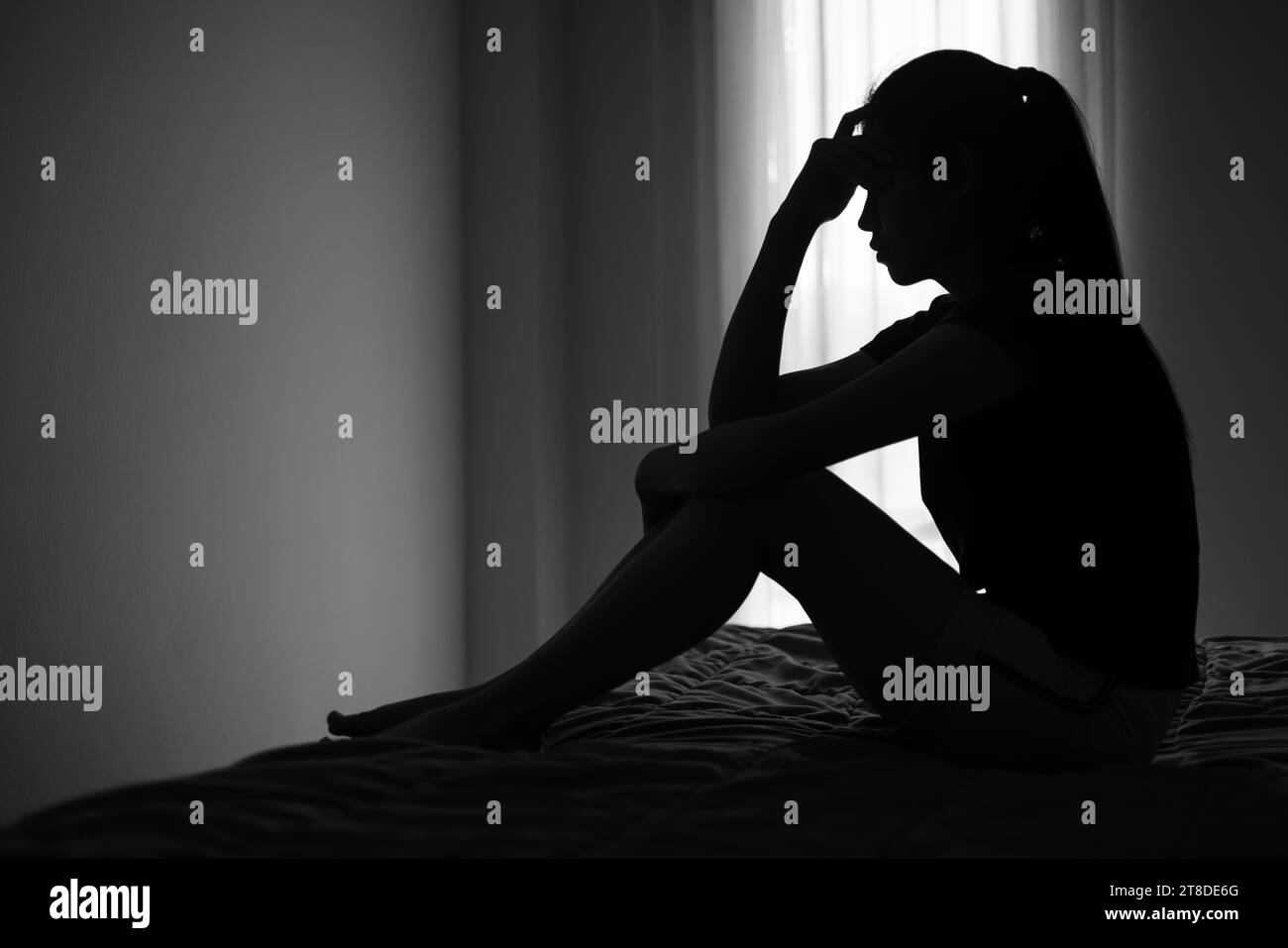Silhouette di donna depressa seduta in camera da letto afflitta da problemi di salute accumulati problemi di relazione di stress. Foto Stock