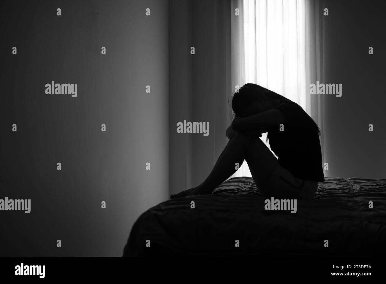 Silhouette di donna depressa seduta in camera da letto afflitta da problemi di salute accumulati problemi di relazione di stress. Foto Stock