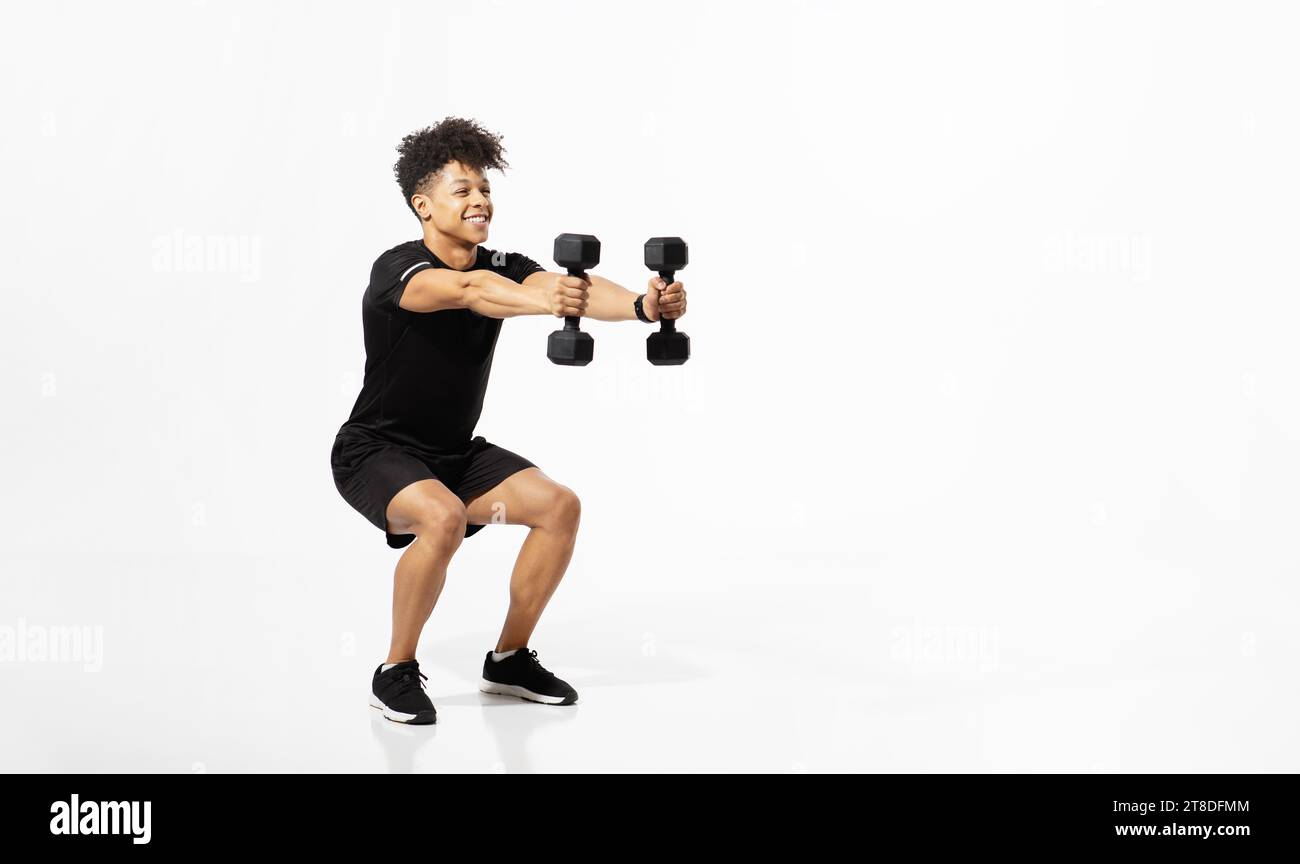 atleta che esegue squat con pesi manubri su sfondo bianco Foto Stock