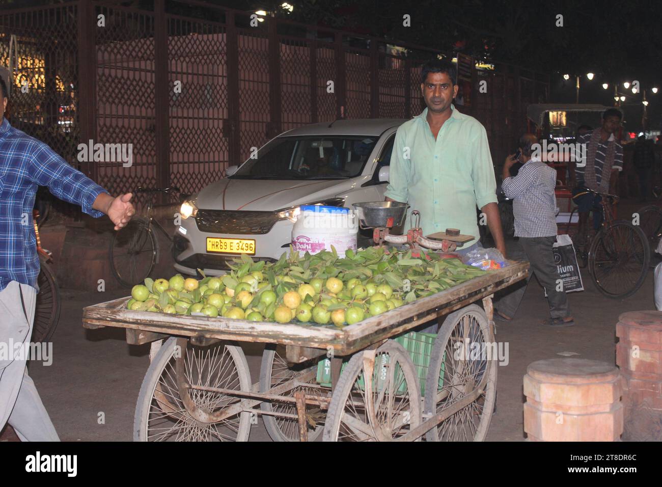 Un falco sconosciuto che vende frutta durante la notte per le strade del mercato Chandni Chowk a nuova Delhi, India, il 14 novembre 2023. Foto Stock