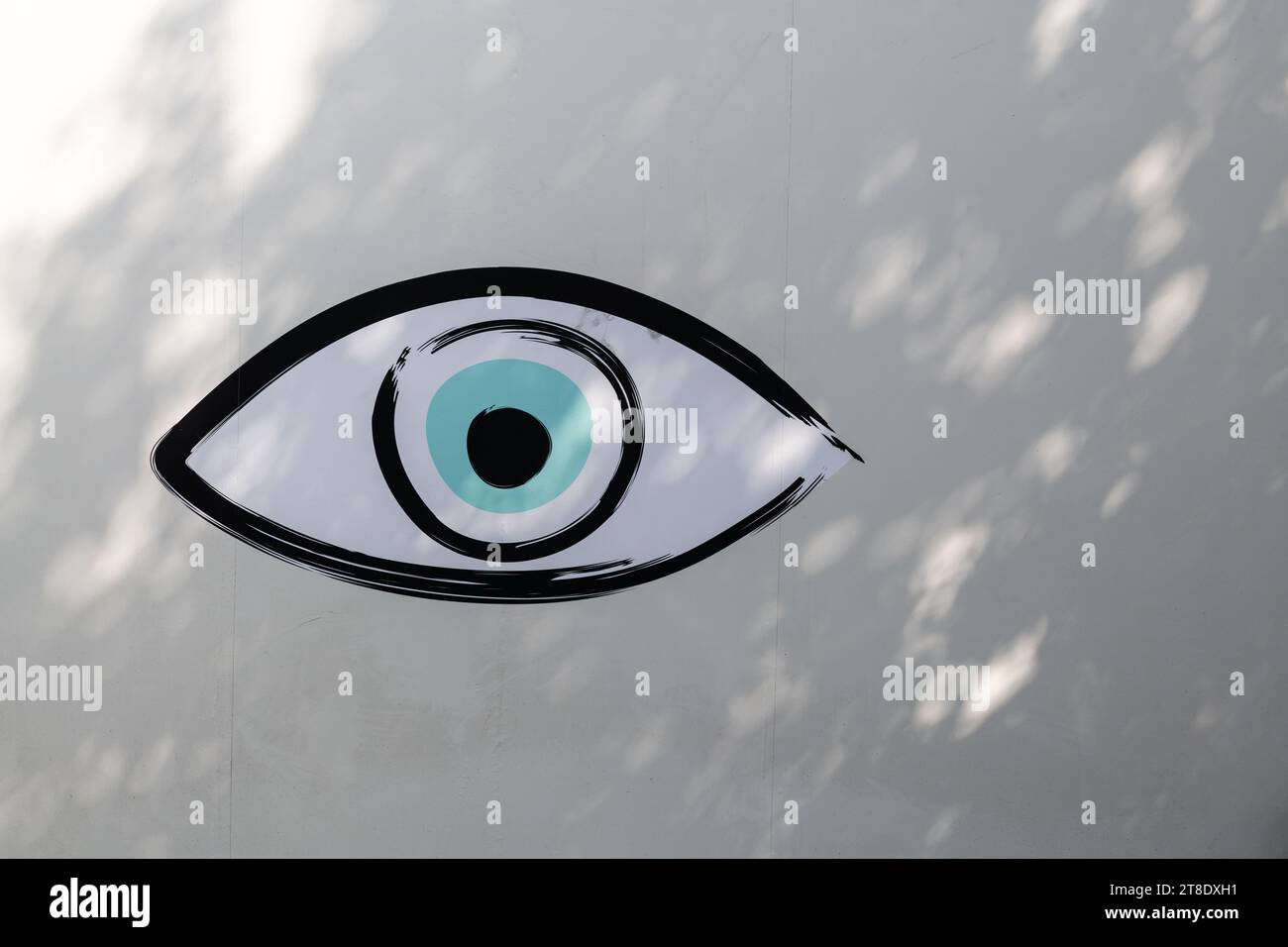 Un grande dipinto di un occhio umano su un muro bianco in stucco. Foto Stock
