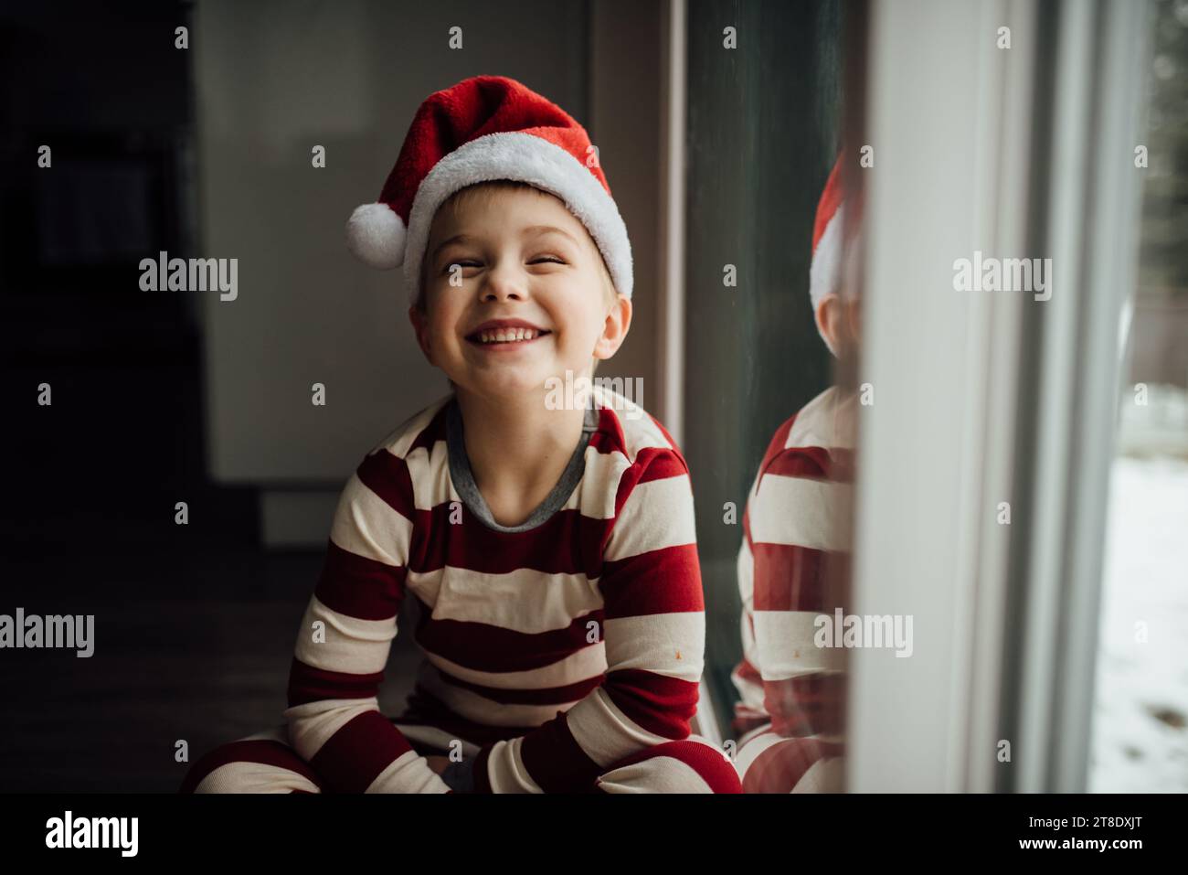 Il bambino sorride enormemente alla macchina fotografica mentre indossa la marmellata natalizia Foto Stock